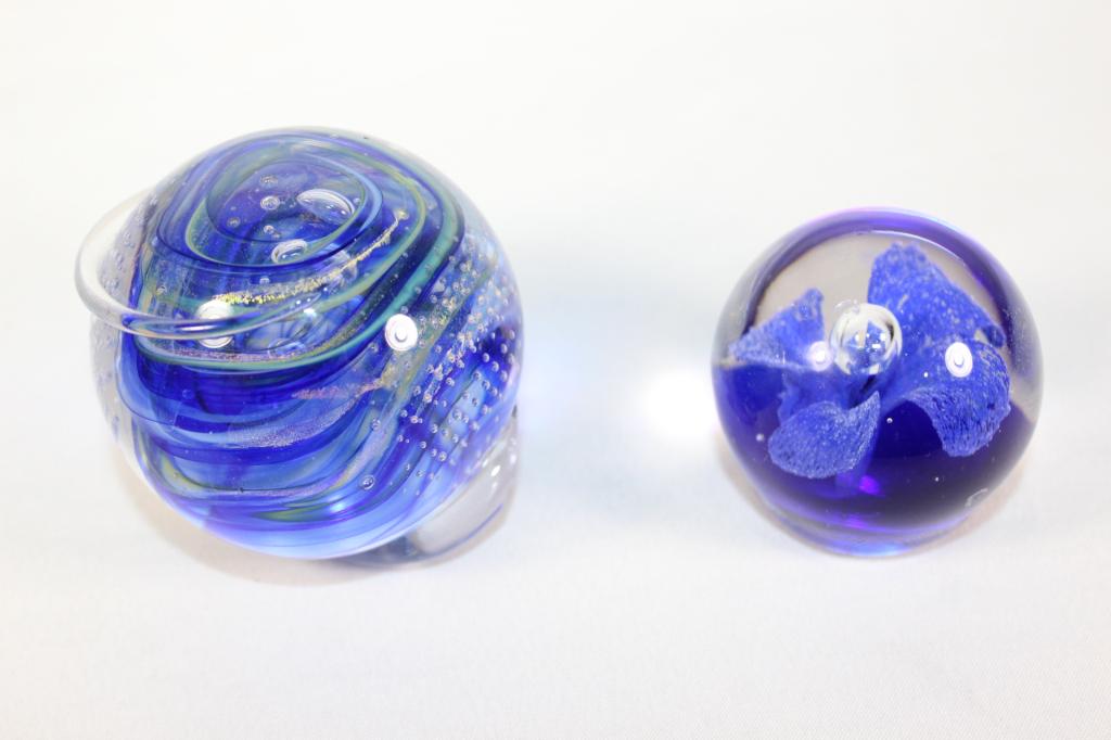 Pair Blue Art Glass Paperweights- Brioni, etc.: Blue Floral Controlled Bubble Art Glass Paperweight- Measures approx. 2.5 by 2.5 inches. Brioni Art Glass Paperweight- Some damage. as pictured