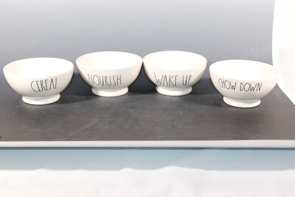 Four Rae Dunn Artisan Collection Bowls: One has nourish on it; another chow down; wake up; and cereal. The bowls are approximately 3 inches high and 5 1/2 inches across.