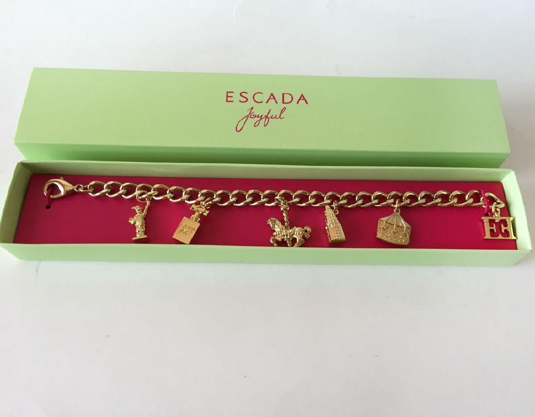 ESCADA: Gold plated curb Cuban link chain lobster clasp: ESCADA: Gold plated curb Cuban link chain lobster clasp JOYFUL bracelet with 6 charms. Charms: STATUE of LIBERTY, PERFUME BOTTLE, CAROUSEL, NY EMPIRE BUILDING, ESCADA SYMBOL. Length 8". Condition exce
