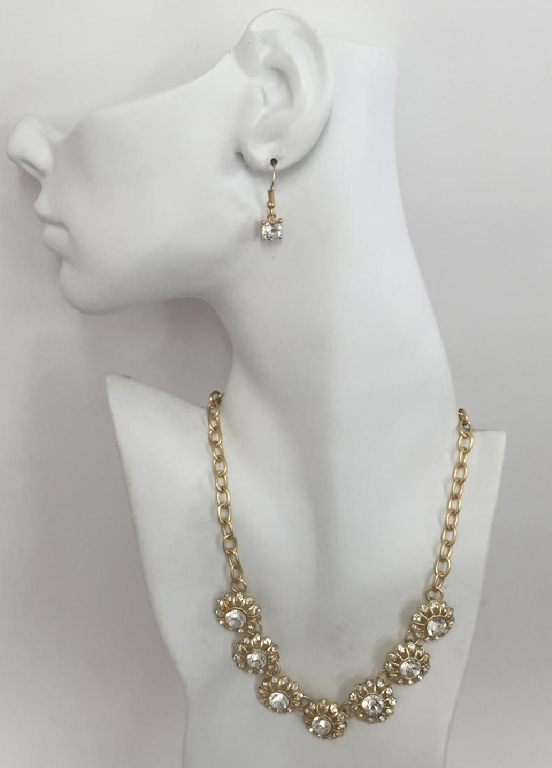 Gold plated satin finish set - necklace and fish hook: Gold plated satin finish set - necklace and fish hook earrings with flower design and white rhinestones. Length of pendant 17 plus 3" extension. Length of earrings 1 1/4". Condition excellent.