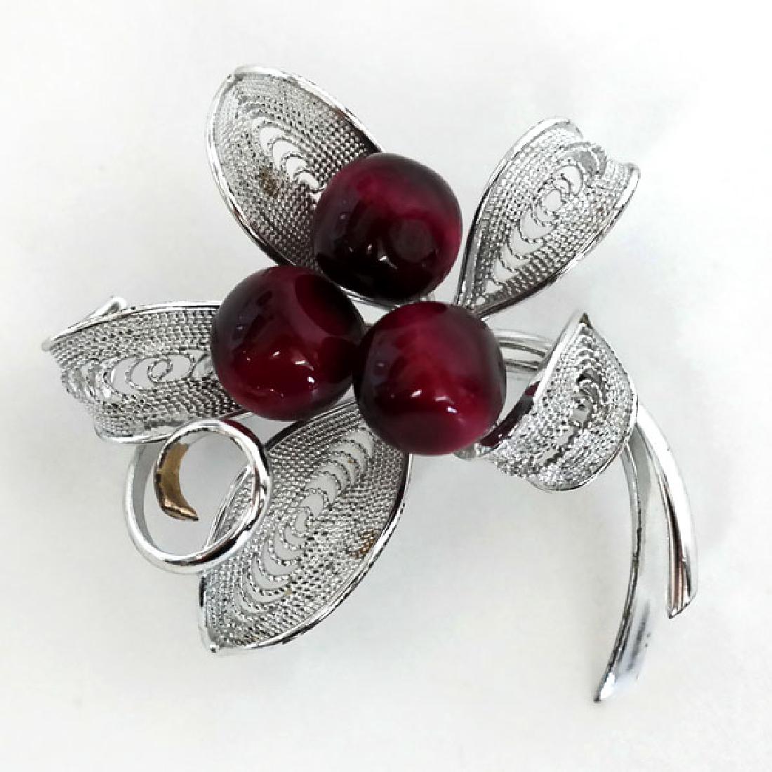 Silver tone pin brooch with filigree leaves and 3 red: Silver tone pin brooch with filigree leaves and 3 red round cat eye beads. Beads measured 8.5 mm in diameter. Length 1 3/4". Condition excellent.