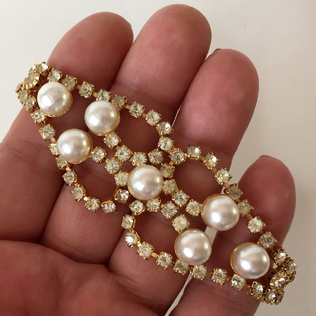 Gold plated hand made flexible bracelet with prongs set: Gold plated hand made flexible bracelet with prongs set white color round shape faceted rhinestones and faux pearls. Clasp hidden, width on front 1 1/8". Pearls measured 8 mm in donated each. Length 7