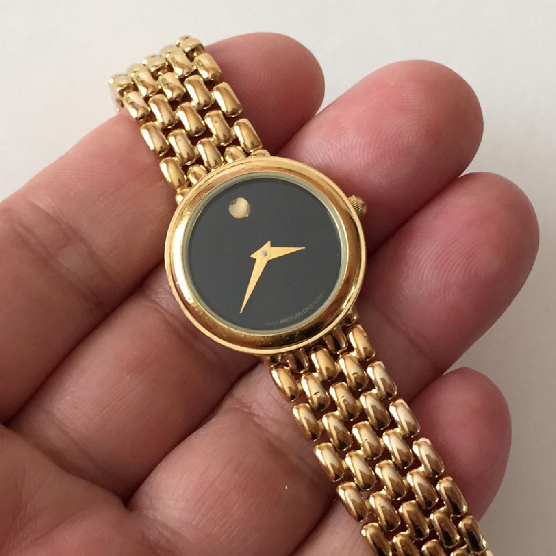 Gold plated round MOVADO Swiss black dial watch with: Gold plated round MOVADO Swiss black dial watch with original bracelet. Stainless steel back, water resistant. Case measured 25 mm in diameter, thickness 5.7 mm, width of bracelet 12.5 mm. Will fit wr