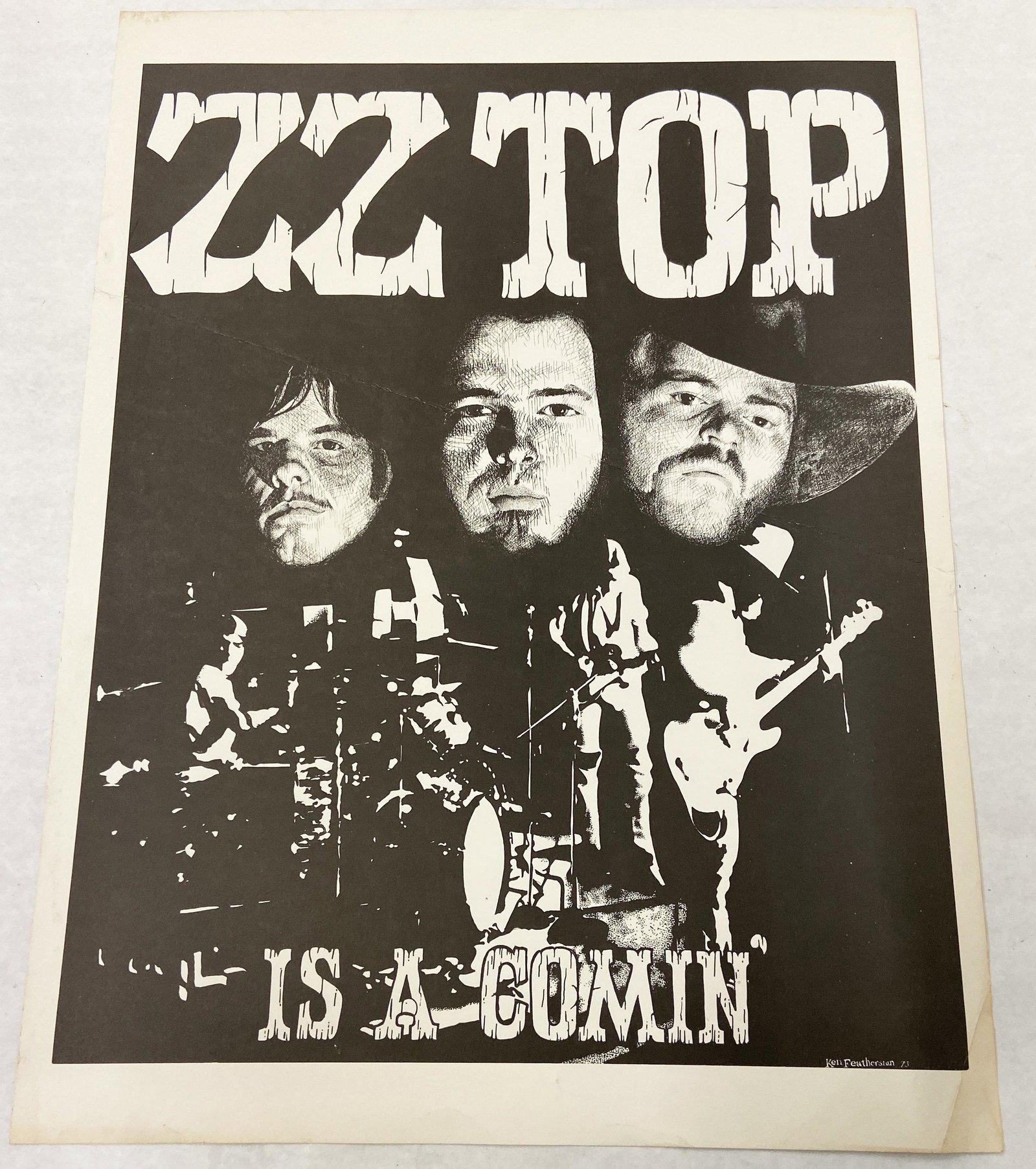 Vintage 1973 ZZ Top Concert Poster.: "ZZ Top - Is a Comin'". The poster has a crease that runs through its entire center. There is also a crease in the corner. Measures 23" x 17". Poster by Ken Featherston.