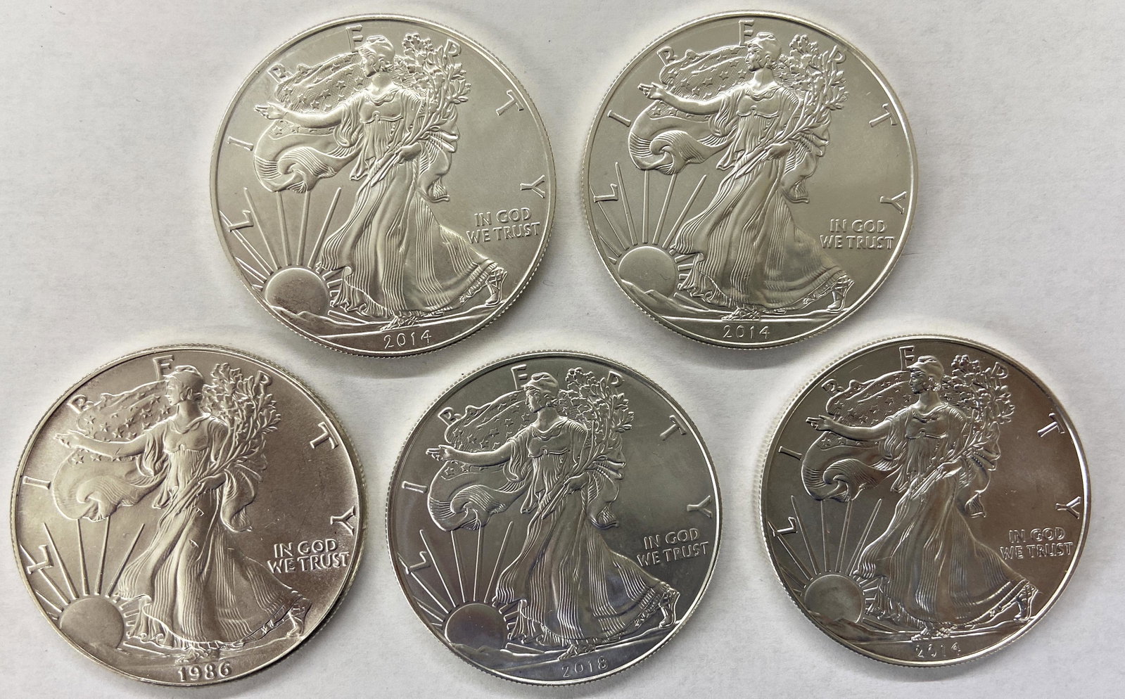 Lot of Five Silver Eagles.: Uncirculated or About Uncirculated. One 1986, One 2018, and Three 2014.