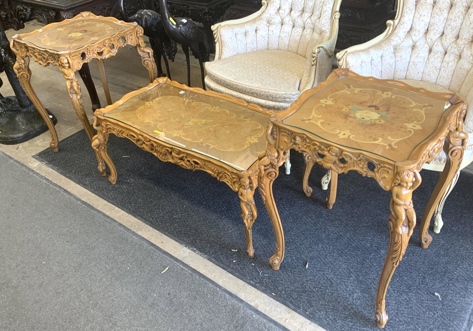 3 Pc. French Inlaid Coffee Table Set.: With Carved Cherubs. The Surface of the Coffee Table has some Wear on the Edges, but Otherwise it is in Good Shape. The Side Tables Measure 20" Square and 28" Tall. The Coffee Table Measures 37" x 19"
