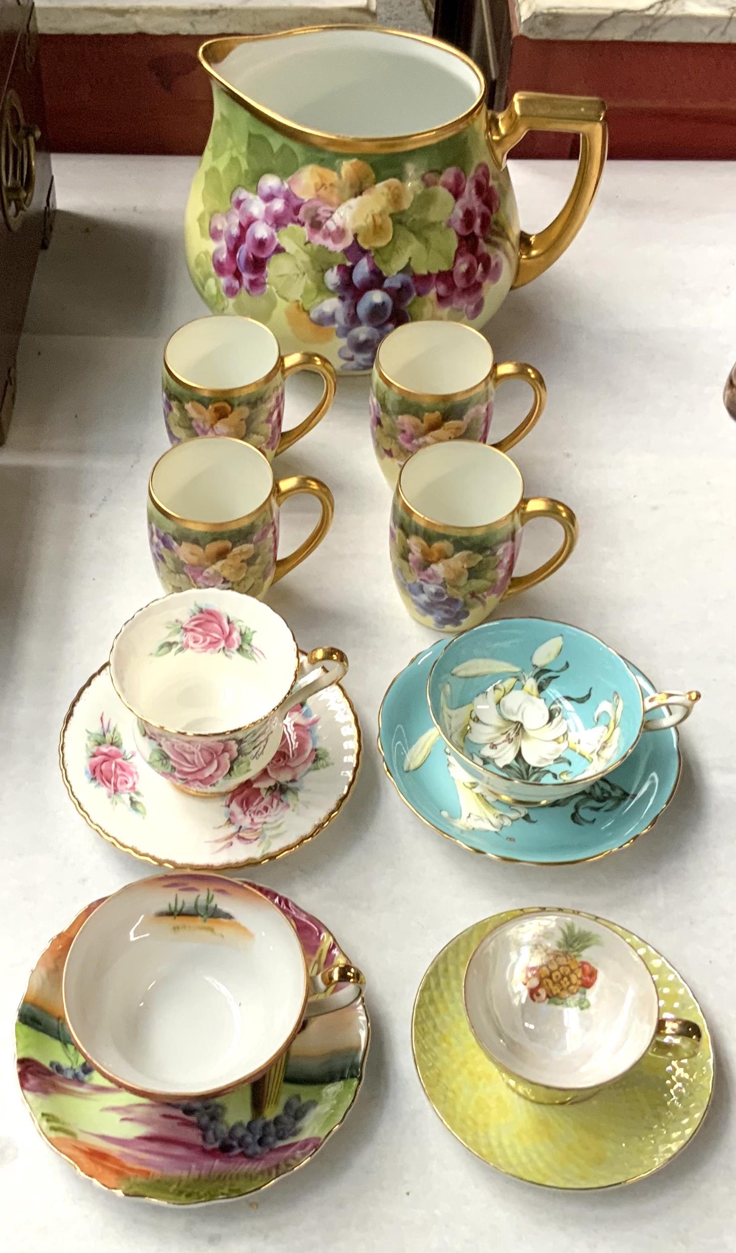 Lot: Bavarian Hand-Painted Pitcher & Mugs, Teacups: Also Included is a Highly Collectable Paragon "Easter Lily" Cup and Saucer Set. The Bavarian Hand-Pitcher Measures 7" Tall and 9" Wide. Other Cup and Saucer Sets, including another Paragon Set, are Pa