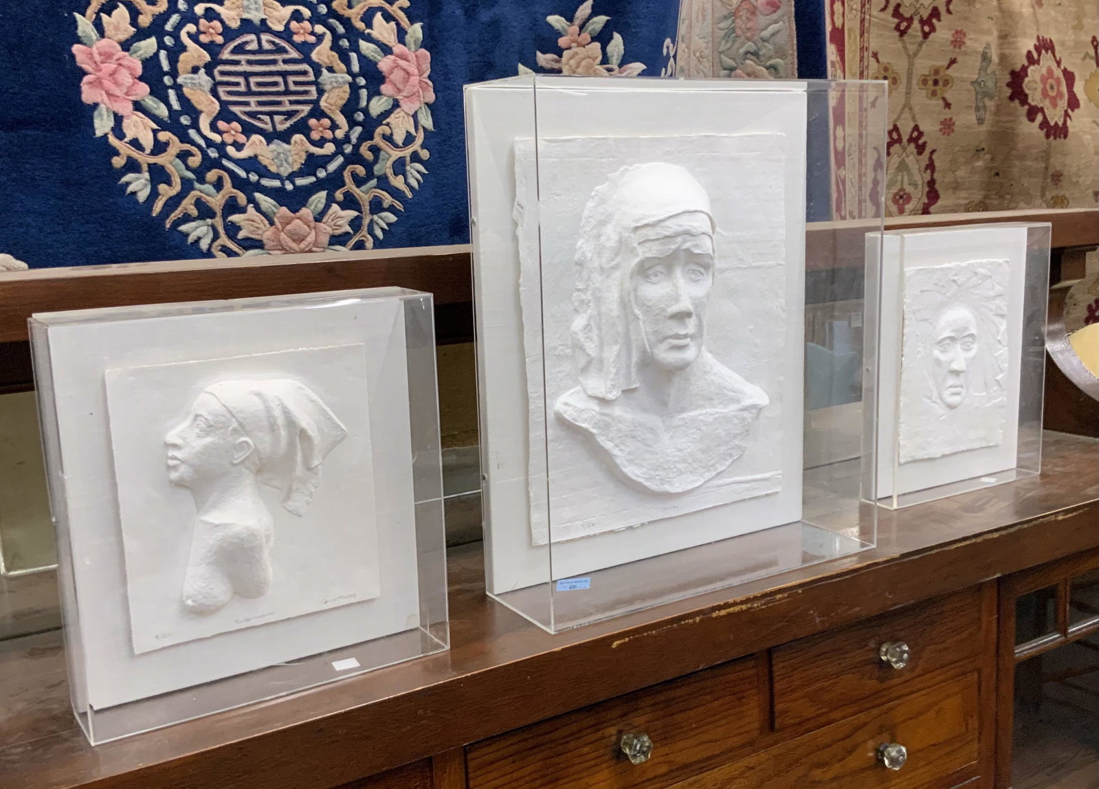3 3-Dimensional Artworks of Faces by Gunthorp.: Limited Edition Pieces, Encased in Lucite. The Largest, titled "Muse", Measures 24" x 20 1/4" x 6 1/4", including the Case. The Others are Titled "Mask" and "Submission". Third-Party Shipping or Perso