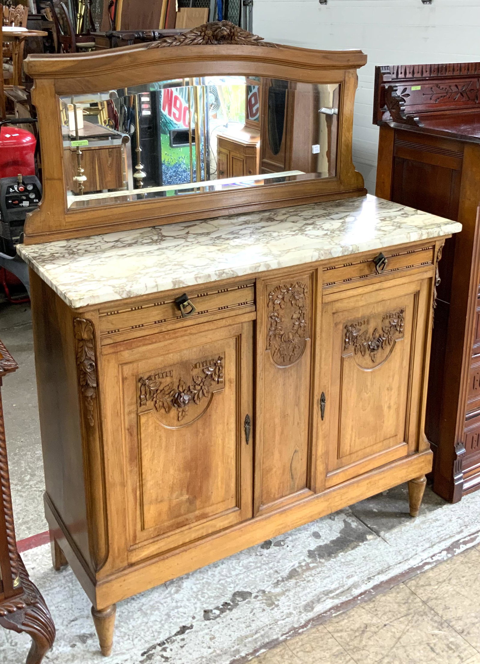 Light Wood Antique Carved Sideboard w/Marble Top.: And with Mirrored Backsplash. In Overall Good Condition, but the Marble has a 12" Crack Running Down it Near the Back. Measures 47 1/2" Wide, 63" Tall, and 18" Deep. Third-Party Freight Shipping or Pe