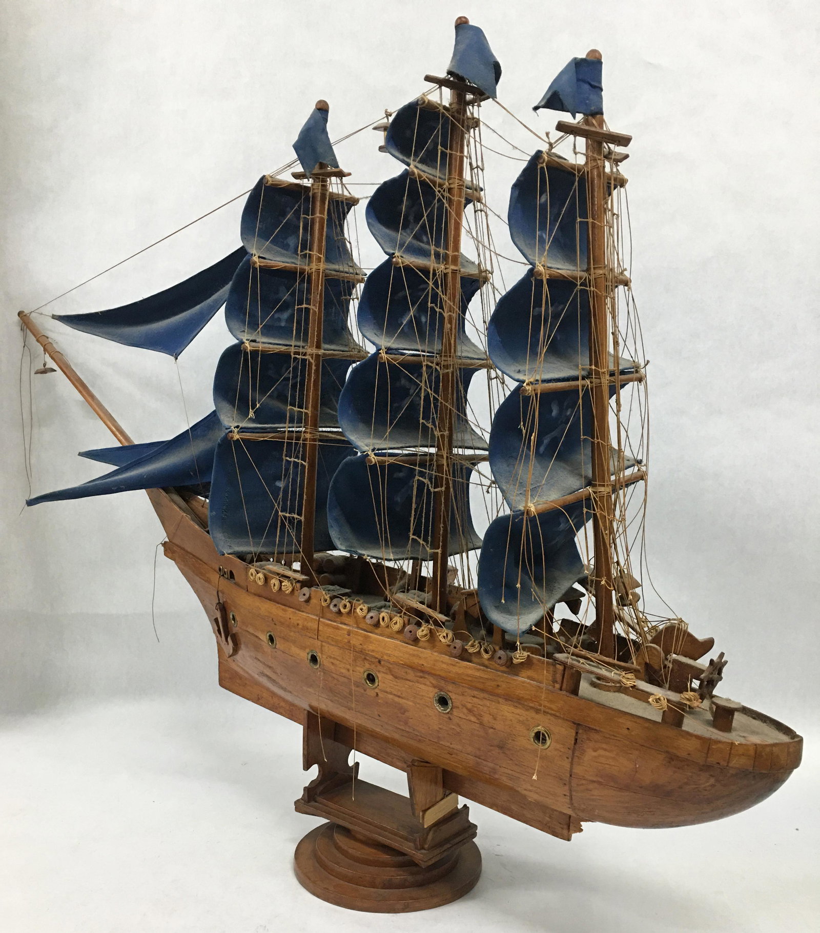 Wooden Model Ship w/ Blue Sails.: About 31" tall, 41" long. Some dust and damage. Third-Party Shipping or Personal Pickup Required.