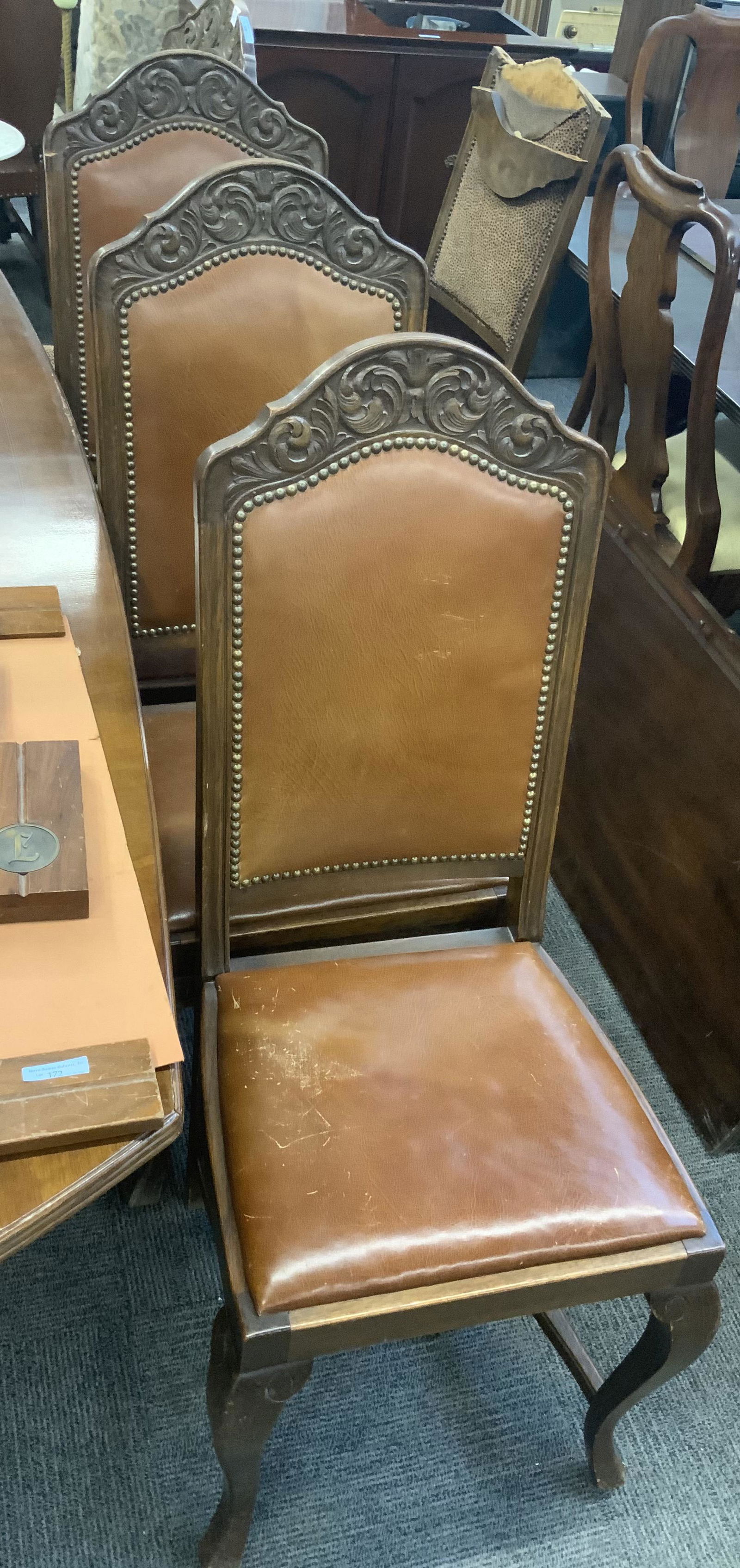 Lot of 5 Dining Chairs.: Three of them have Leather Upholstery, and Two have Leopard Pattern Type Fabric. The Chairs are Carved on Top with a Nailhead Trim. The Top of One of the Chairs is Broken. Third-Party Freight Shipping