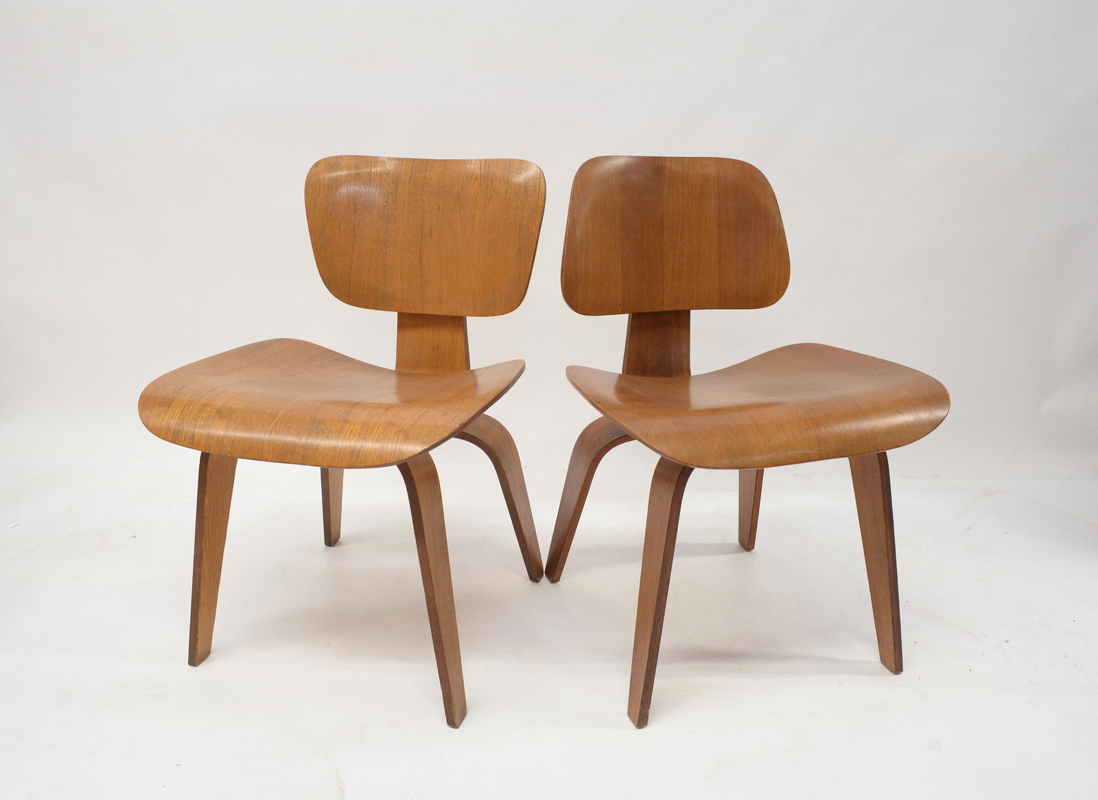 Lot of 2 Charles & Ray Eames Bentwood DCW Chairs.: These have Minor Wear. One has a 2015 Label from Weber Furniture Service (Probably Refinished at that Time). The Back of the Chair with the Inverted Back has a bit of Missing Veneer in One Corner. The