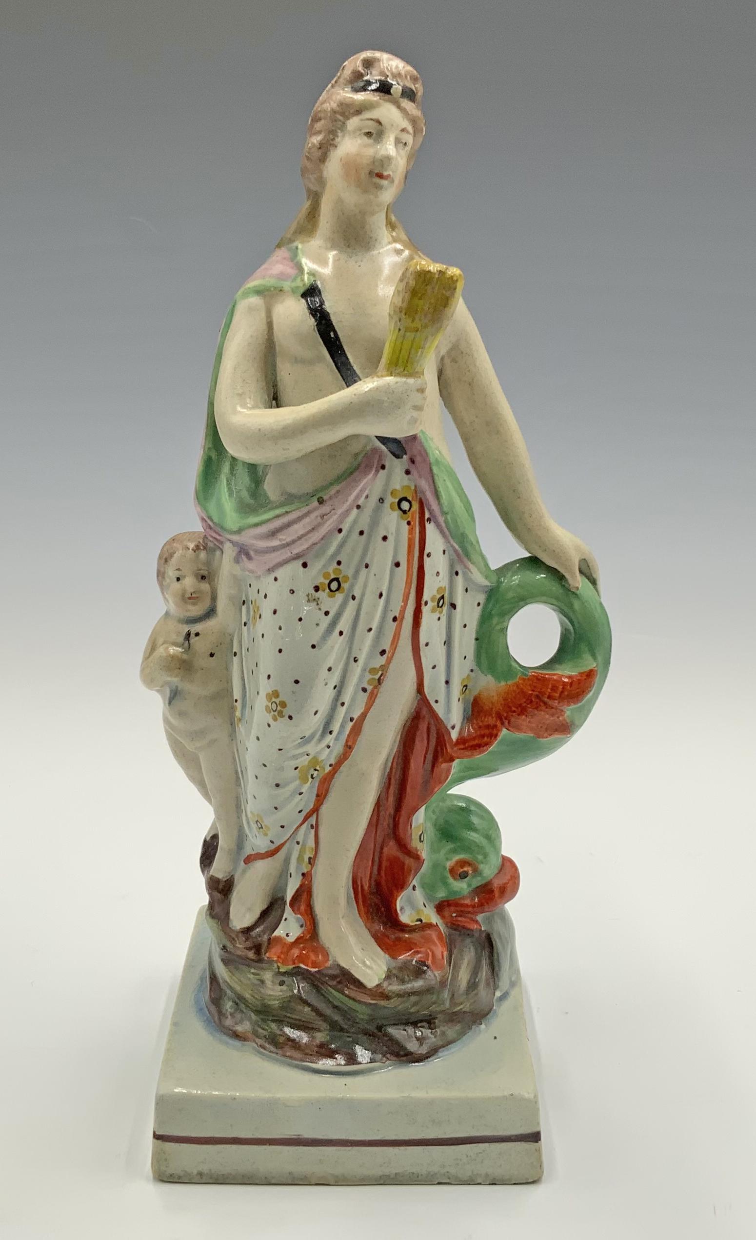 Antique Staffordshire Figurine of Venus w/ Cupid.: 8.5" tall. She is holding onto wheat stalks with one hand, and a giant fish with the other. Some small areas of chipping on her back; overall, good condition.