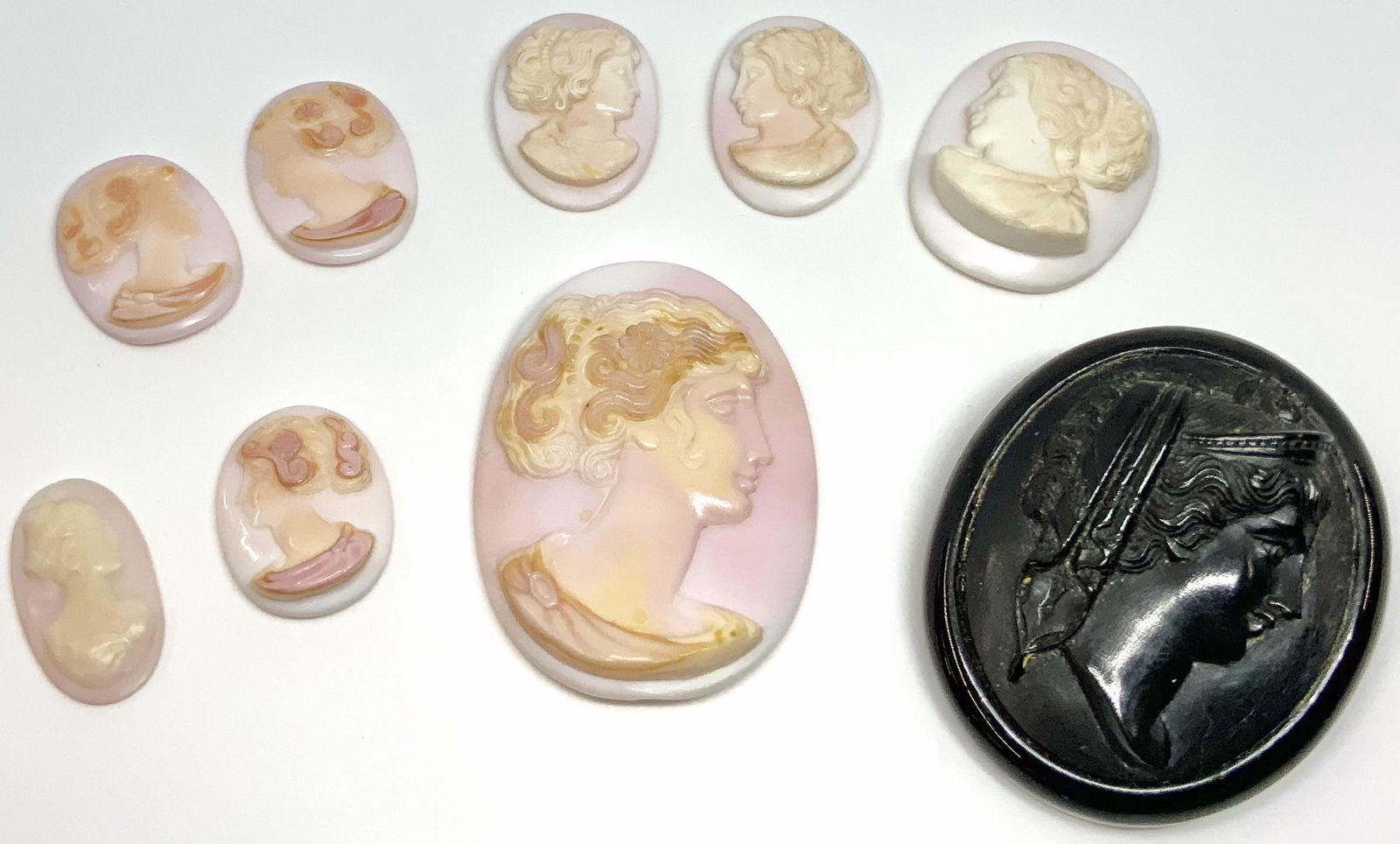 Lot of Cameos and Cameo-Style Pin.: The Dark Pin looks to be made of Bakelite or Plastic. It measures just over 1 3/4" Long. The Cameos look like they are shell, but are actually made of Plastic, and are all unmounted. They range in siz