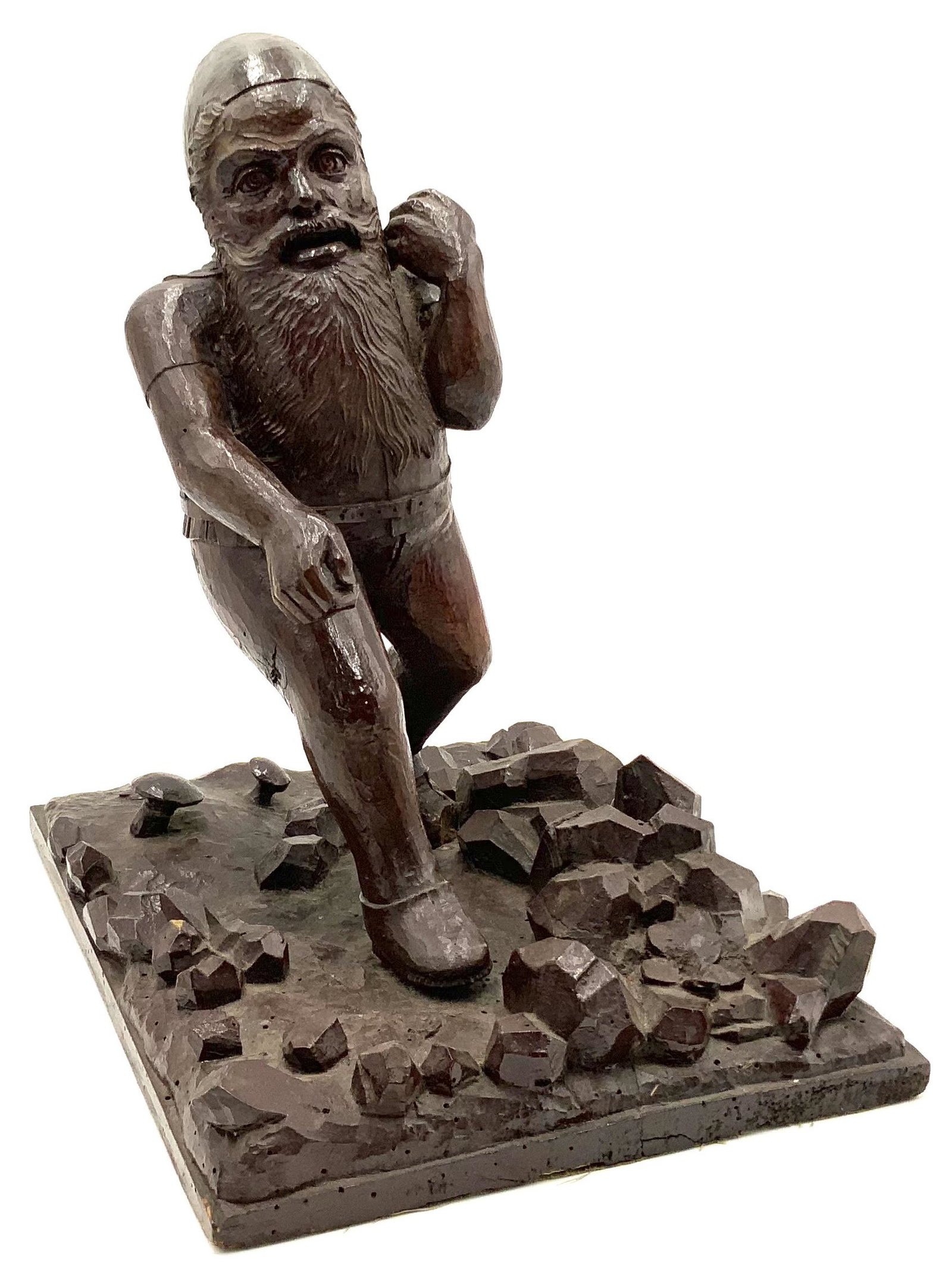 Black Forest Carved Sculpture of Gnome.: The gnome is surrounded by stones, mushrooms, and flowers. He is a little Wobbly on the base. There are signs of Wear, and there is Dust in the recesses. There is also a crack by his left foot. It loo