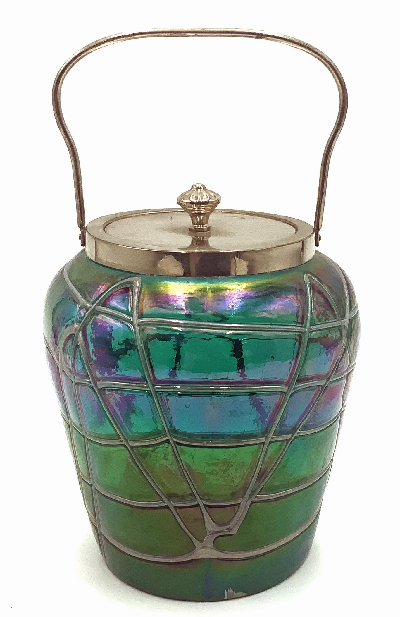 Loetz? Iridescent Art Glass Biscuit Jar w/ Handle.: No signature has been found on the Piece. The Glass has blue, green, and purple tones, with a silvery ribbon design. The Item appears to be in Very Nice condition. It measures 6 1/2" tall, not includi