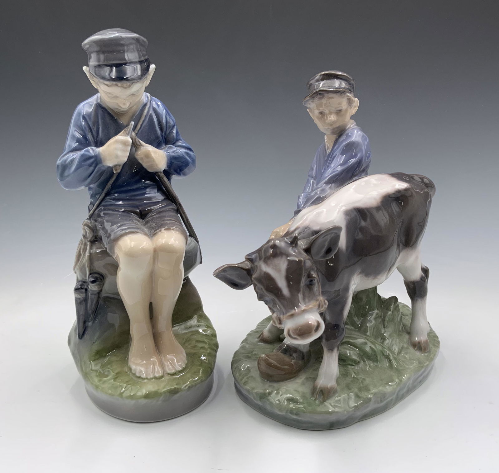 Lot of 2 Royal Copenhagen Country Boy Figurines.: Both are Signed by artist Christian Thompson. They are marked on the Undersides, numbered 905 and 772. They both look to be in Great cosmetic condition. The larger one measures 7" tall and 6 1/2" long