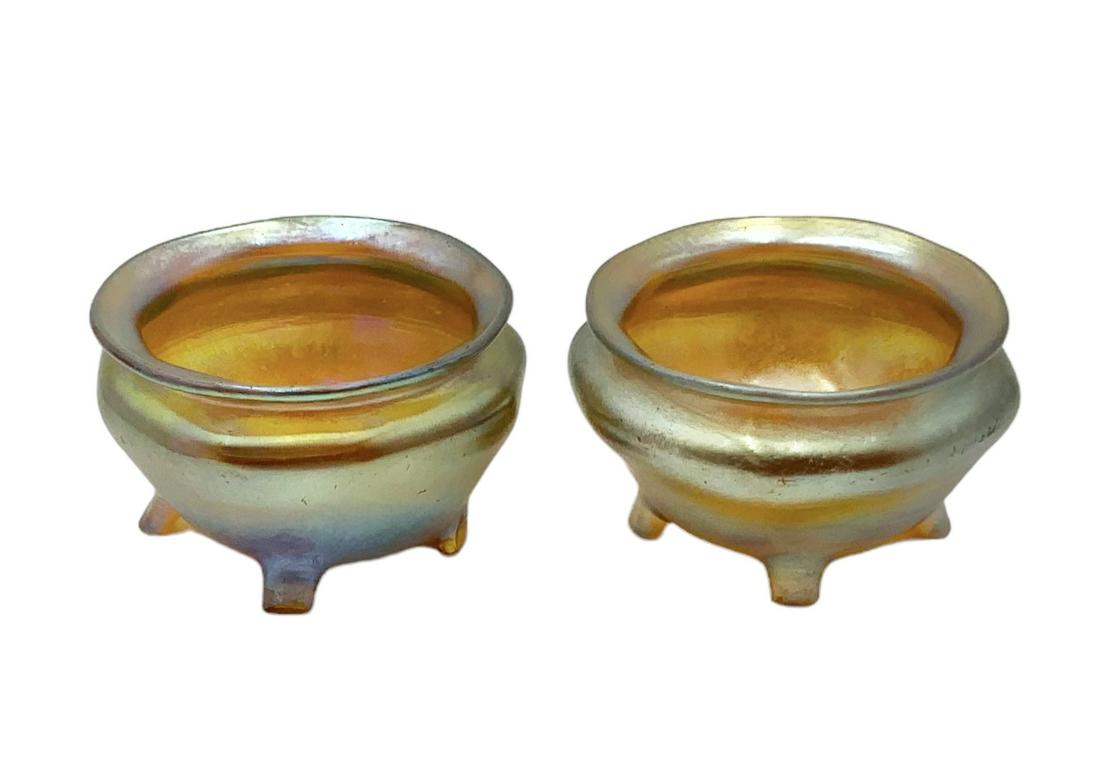 Pair of Tiffany Favrile Art Glass Salt Cellars.: These are Iridescent glass salt bowls, each with four little feet. They are Signed, "L.C.T." on the Undersides. They are in Nice condition overall. They measure 2 1/4" in diameter and 1 1/4" tall. In-