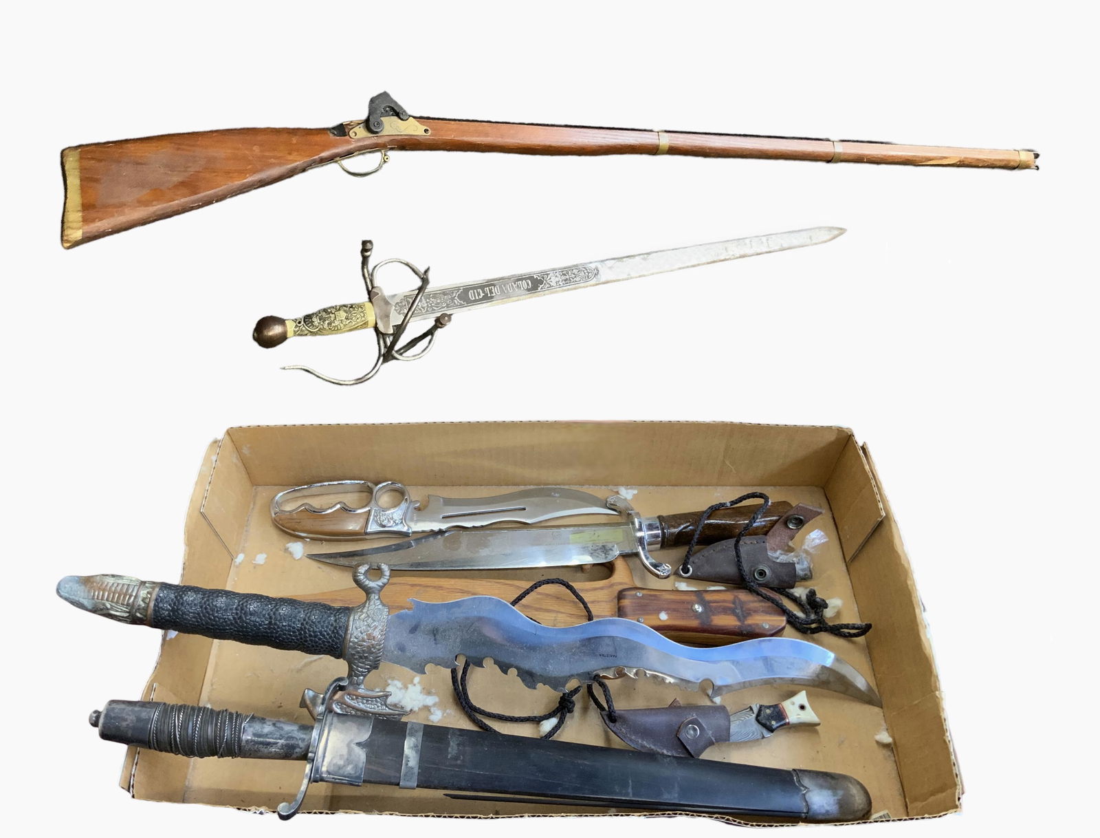 Lot of Asst. Weapons, Mostly Knives & Swords.: The lot Includes a "Colada Del Cid" sword, a reproduction Bowie knife, a dagger with a dragon handle, a dagger with an eagle handle, and more. The largest item is the imitation rifle, measuring 52" lo
