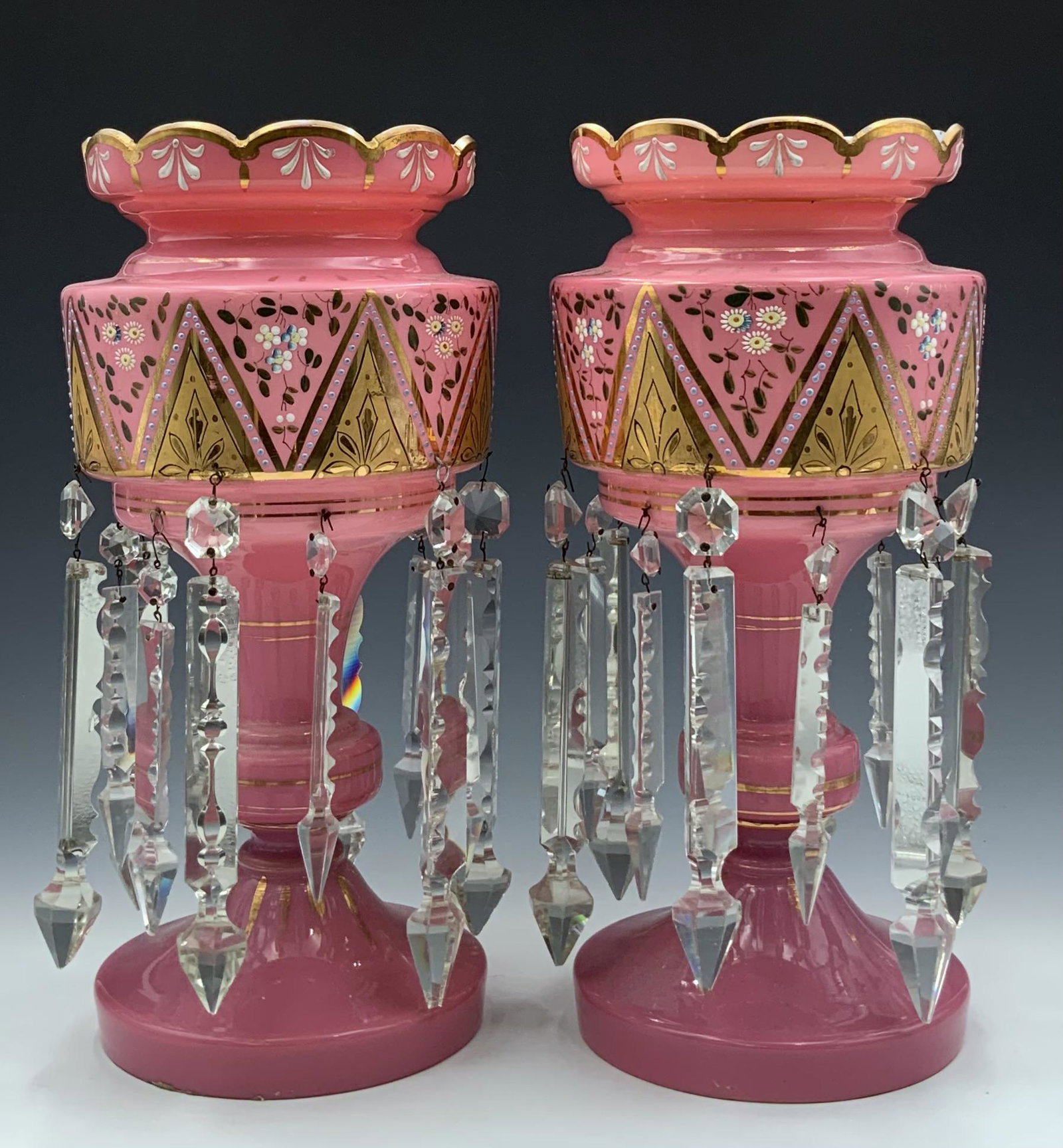 Pair of Pink Glass Mantel Lustres w/Crystal Prisms: These are Decorated with flowers and gold designs. They look to be in overall Good condition, with some Paint Loss. There is one dangling prism missing. Each measures 15" tall, and 7" in diameter. In-