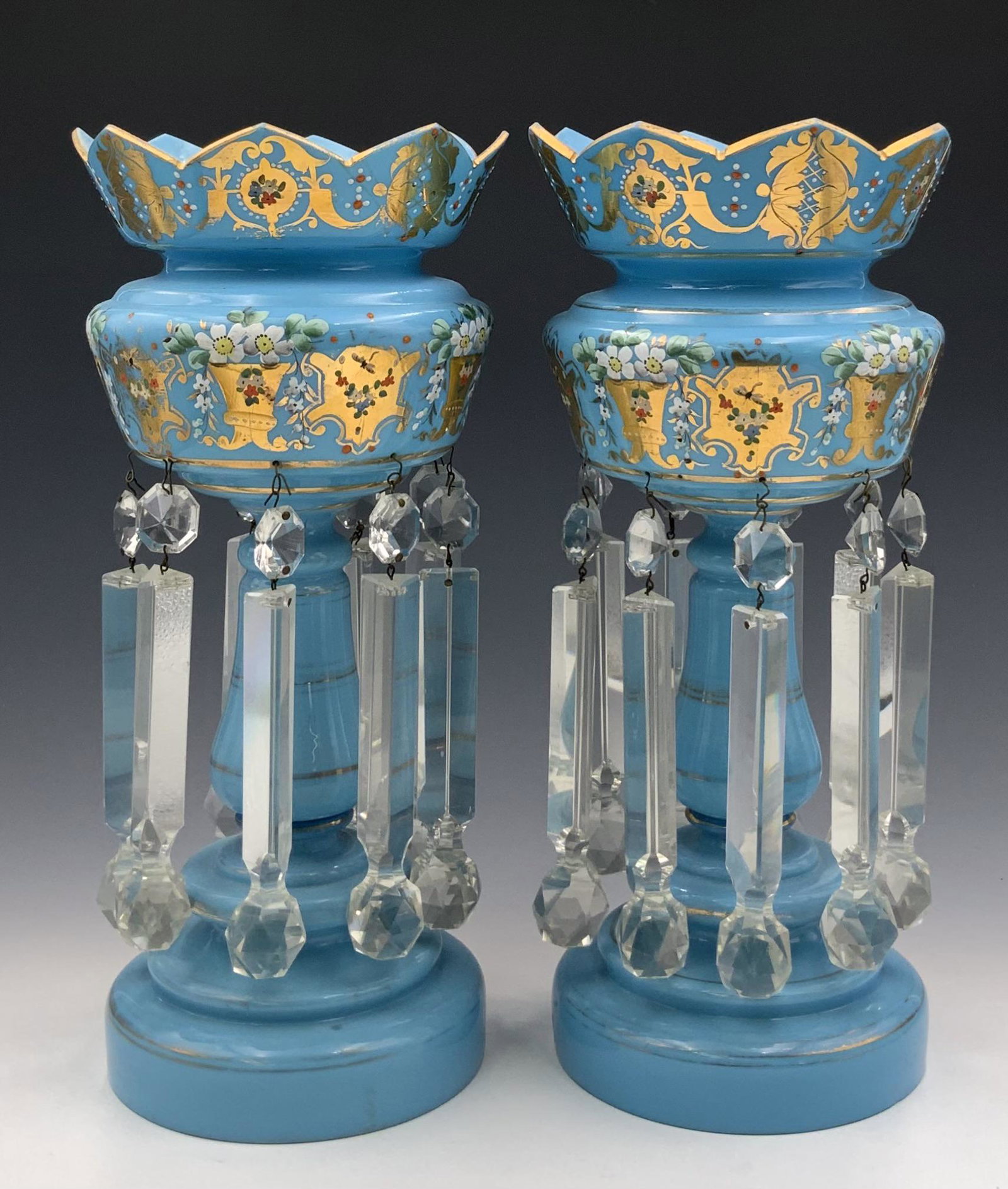 Pair of Blue Glass Mantel Lustres w/Crystal Prisms: These are Decorated with flowers and gold designs. They look to be in overall Good condition, with some Paint Loss. Each measures 14 1/2" tall, and 7" in diameter. In-House Shipping is Available. Plea