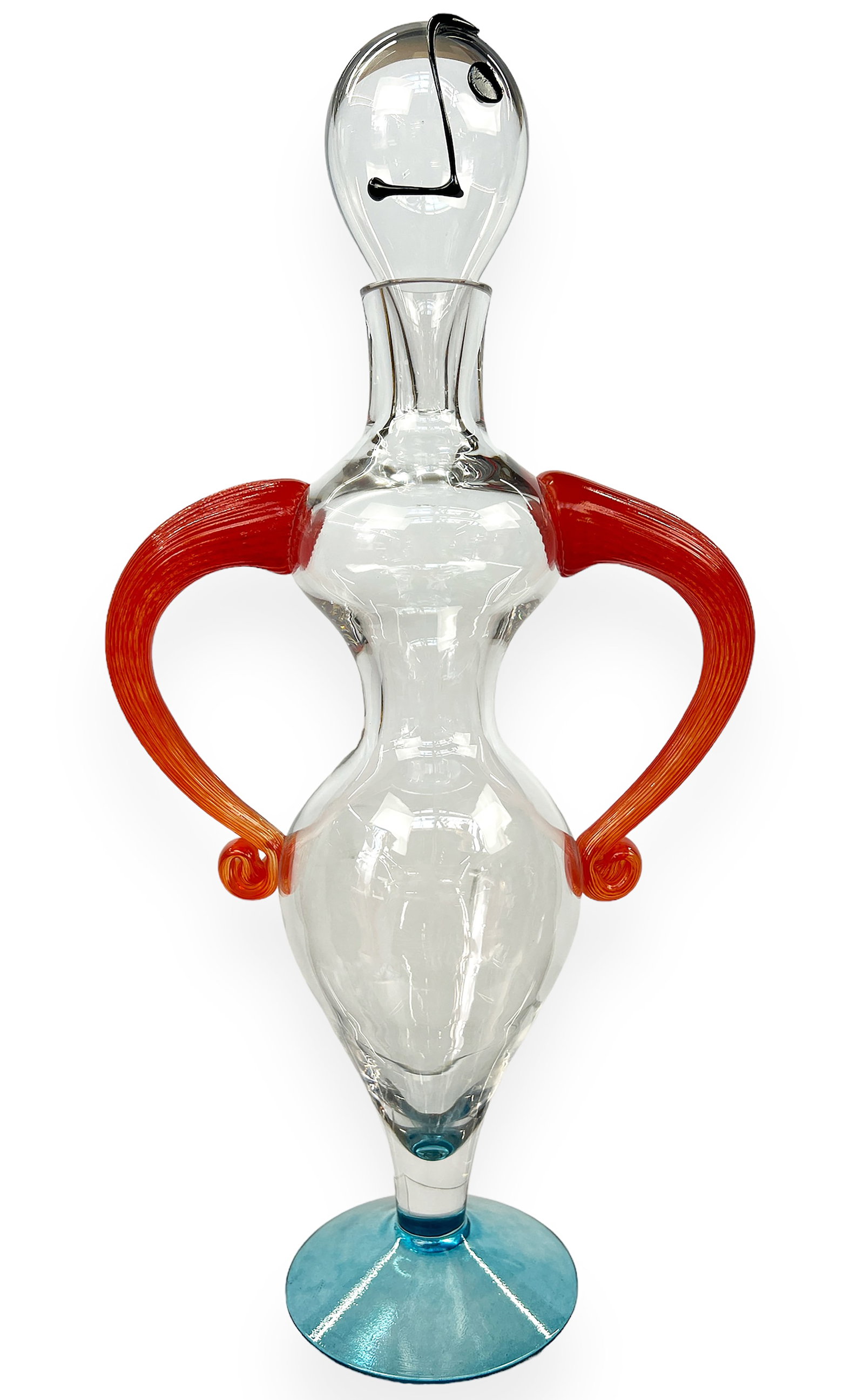 Art Glass Decanter, Kjell Engman for Kosta Boda.: This figural art glass decanter is signed " Kosta Boda, K. Engman, 89207" on its underside. The sculpture has an hourglass body, orange arms on its hips, and an abstract stopper. The piece is in good 