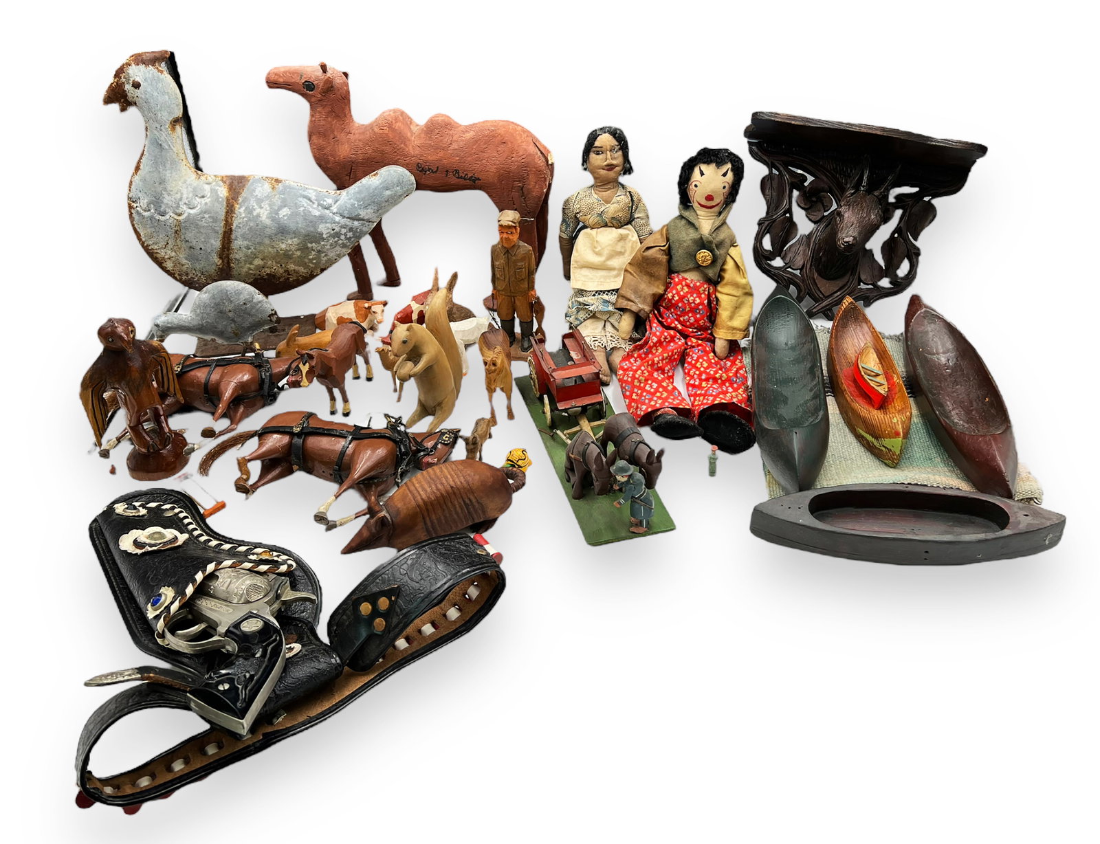 Lot of Carved Folk Art Figurines and Toys.: This is a lot of mostly primitive wooden figurines, though there are also a couple of dolls, as well as a toy cap gun. Most of the figurines depict animals, but there are also five carved wooden boats