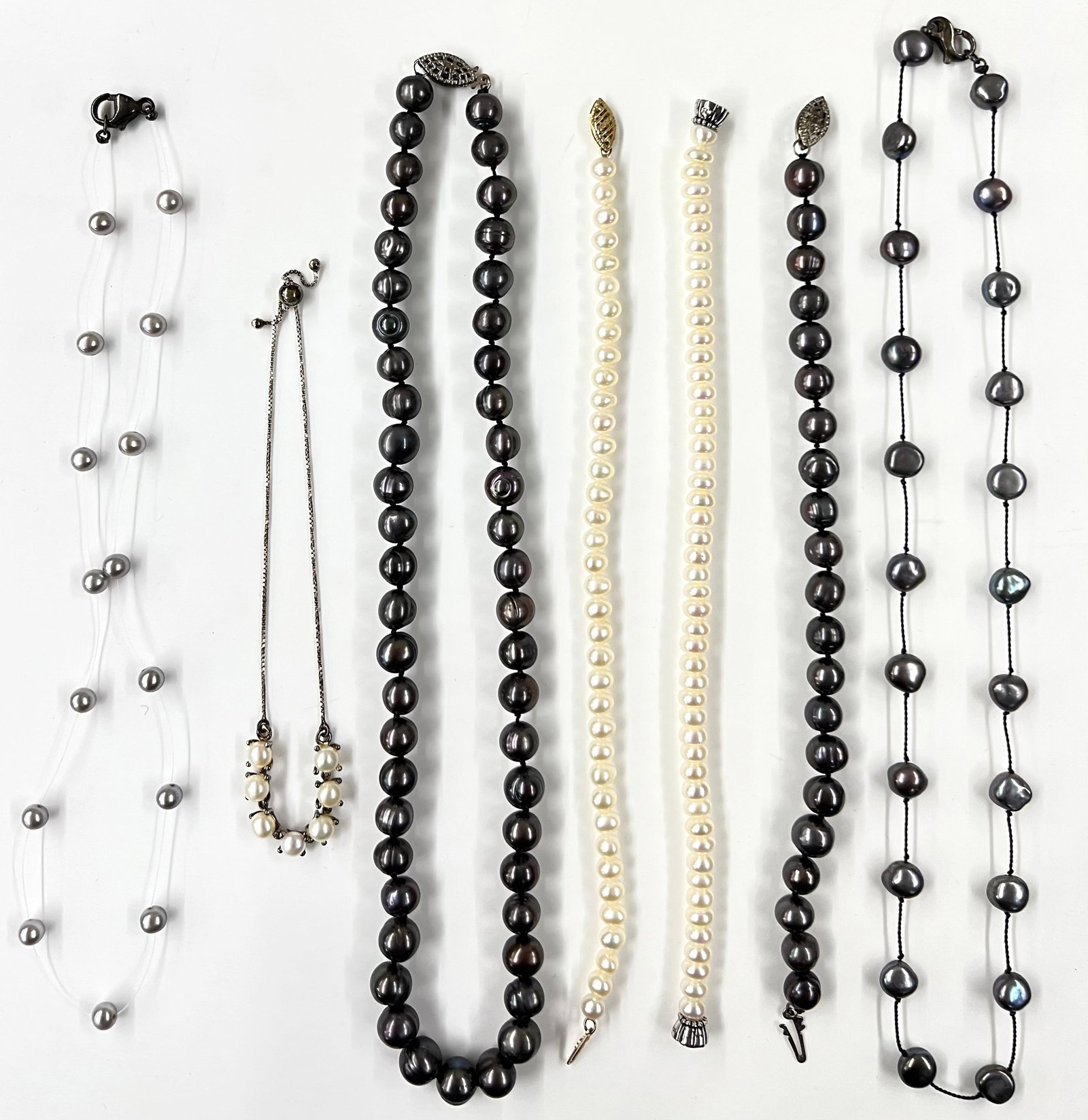 Lot of Pearl Necklaces and Bracelets.: The lot includes some dark-colored pearls. One of the Bracelets has a 10K Gold Clasp. One of the Bracelets is Silver and Pearls. This bracelet is adjustable. The necklaces measure 15" to 17 1/2" long.