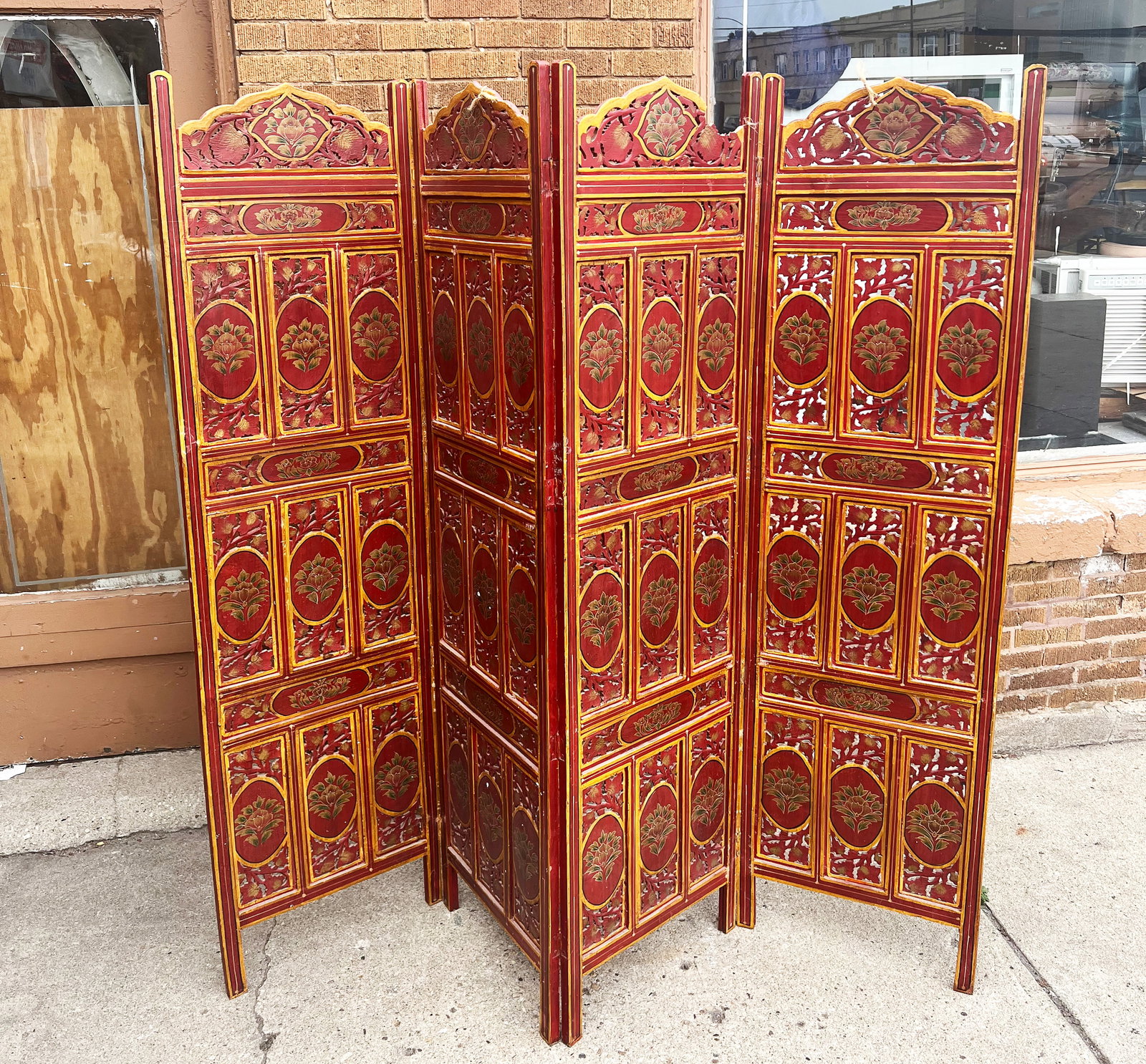 Carved Four-Panel Screen.: The screen is painted red, with yellow trim, and features a floral motif. It is in used condition, with some paint loss. Each of the panels measures 72" tall and 20" wide. Third-Party Freight Shipping