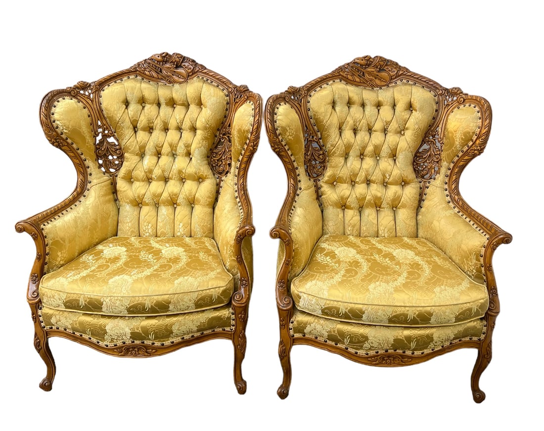 Pair of French Carved Chairs.: This is a pair of nicely carved wingback chairs with button tufted backs and nailhead trim. Both of these gold upholstered chairs feature carvings of violins and flowers. They are in good used conditi