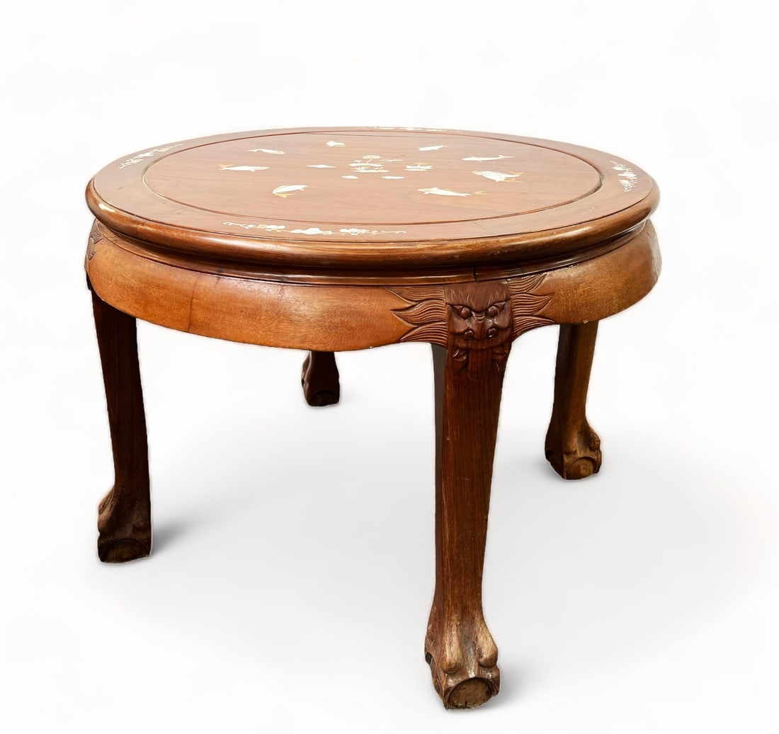 Chinese Table with Mother of Pearl Inlay.: This is a round Chinese table made from light wood which features carved feet and sides, as well as mother of pearl inlay. There is a crack in the top, as well as some scratches and scuff marks. It me