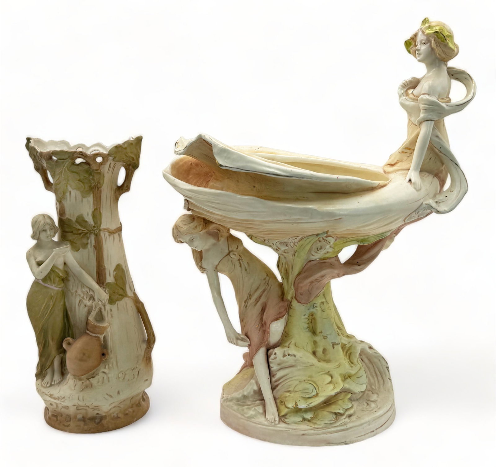 Lot of 2 Royal Dux Art Nouveau Figural Vases.: Both are Signed. The smaller piece depicts a partially nude woman with a jug of water. The larger piece depicts two women in dresses lounging near a shell-like vessel. This larger item measures 13" x 