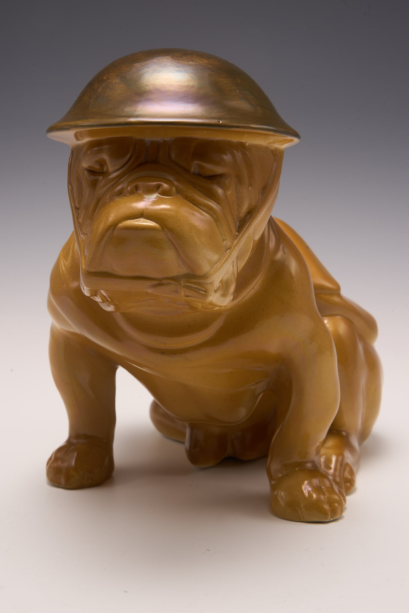 Royal Doulton Bulldog Figure w/ Military Helmet.: This Large dog is caramel-colored, and is wearing a World War I military helmet. It looks to be in very nice condition. The Royal Doulton mark is visible on the underside of the figure. The dog's dime
