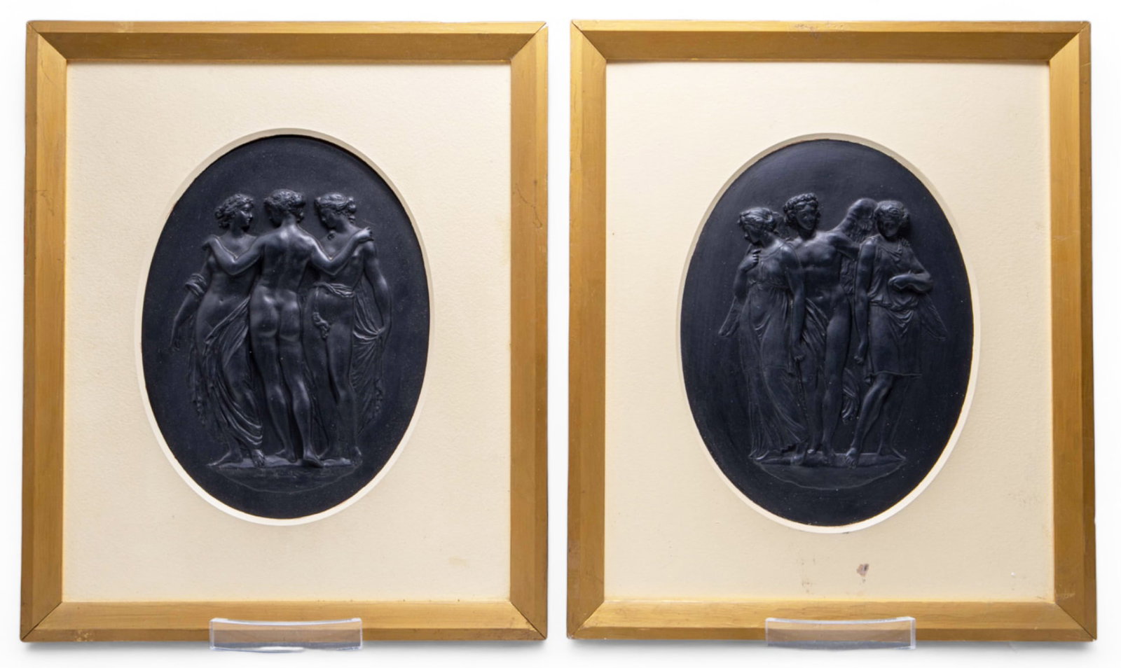 Pair of Wedgwood Black Basalt Ware Plaques.: They are Neoclassical relief plaques - one depicts the "3 Graces", the other depicts a nude angel standing between a couple. Both oval plaques are housed in painted frames. The frames have some scratc