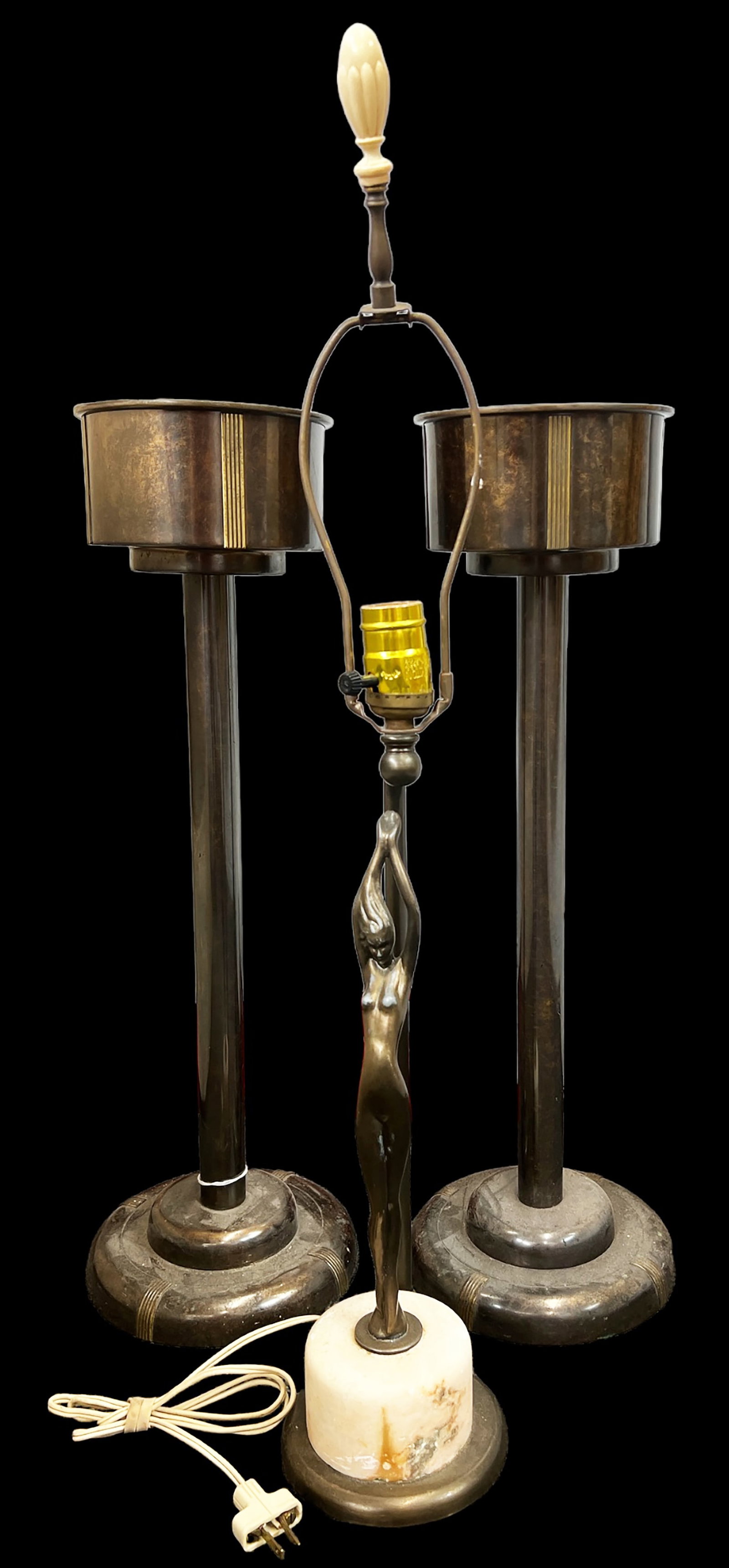 Pair of Ashstands and a Lamp.: Included in this lot is a pair of silver crest arts and crafts style standing ashtrays, as well as a deco style lamp. One of the ashtrays has a brass mesh cover. The deco lamp features a nude woman on