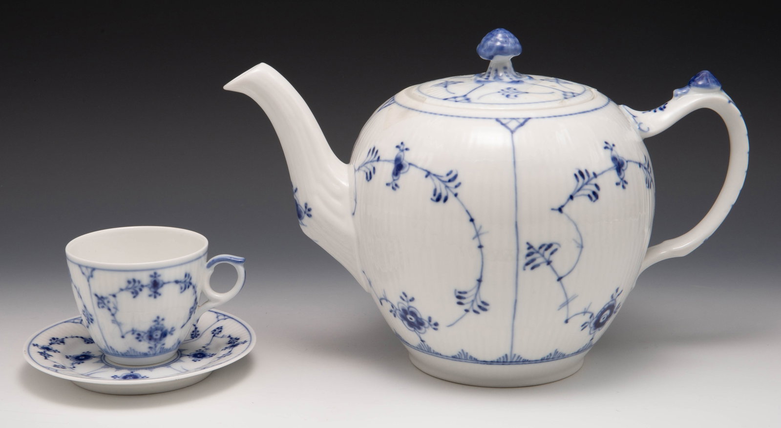 Lot of Royal Copenhagen Items - Blue Fluted Plain.: This lot includes a teapot w/ lid and mushroom finial, numbered 1/259. The demitasse cup w/ round handle is numbered 1/ 298. The small plate is numbered 1/400. It appears to have a small flaw along th