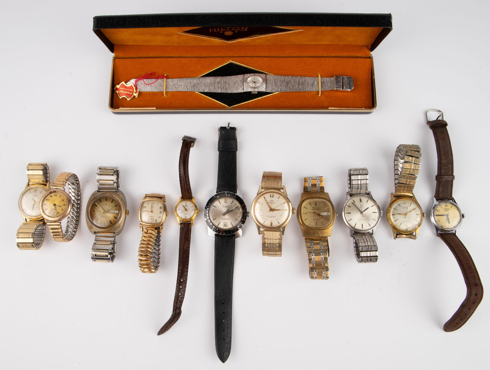 Lot of 12 Vintage Watches - Elgin, Waltham, Etc.: The lot contains 12 vintage watches, 10 of which tick. The brands included are Hilton, Clinton, Elgin, Waltham, Aureole, Bucherer, Gruen, Helbros, Bulova, Omega, and Sheffield. One of the Elgin watche