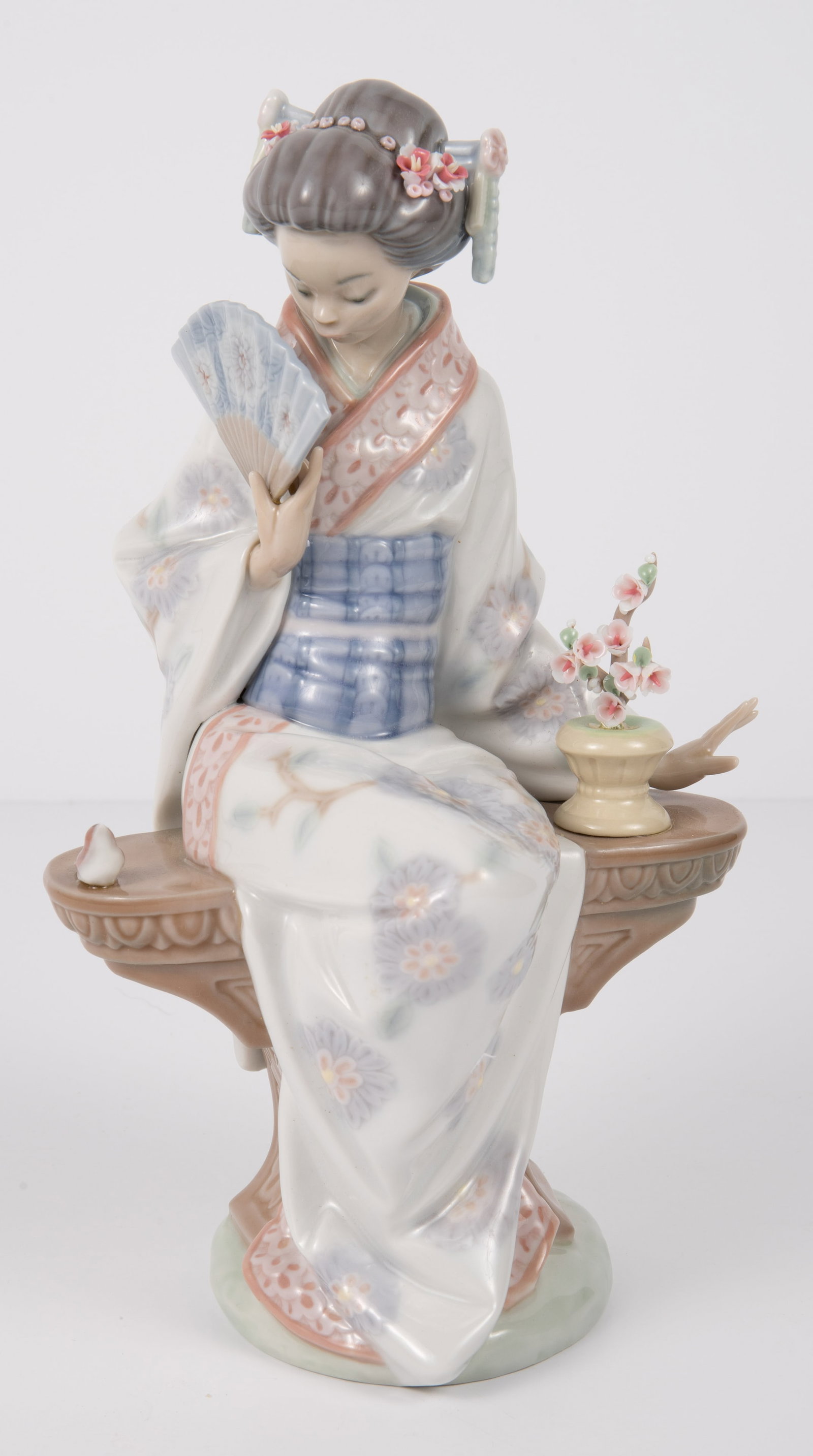 Lladro Nippon Lady Figurine w/ Original Box.: The figure is of a Japanese woman in a traditional kimono, seated on a bench next to a little bird. The glaze or adhesive in the flower vase is a bit thick, but overall, the figure looks to be in nice
