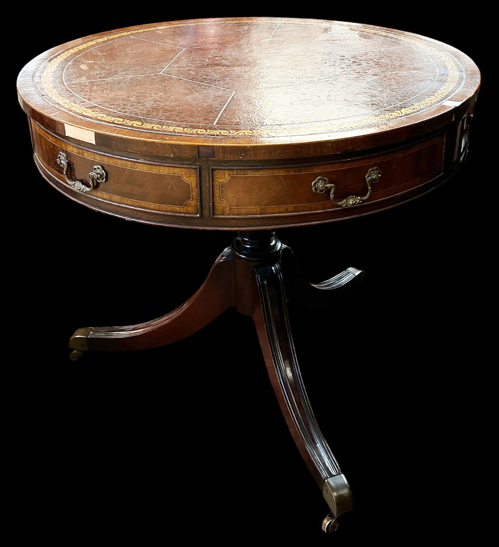 Mahogany Drum Table.: This table has an embossed leather top and Duncan Phyfe legs. There are two drawers and two dummy drawers. The legs have brass casters. There are some scratches and some veneer loss along the edges of