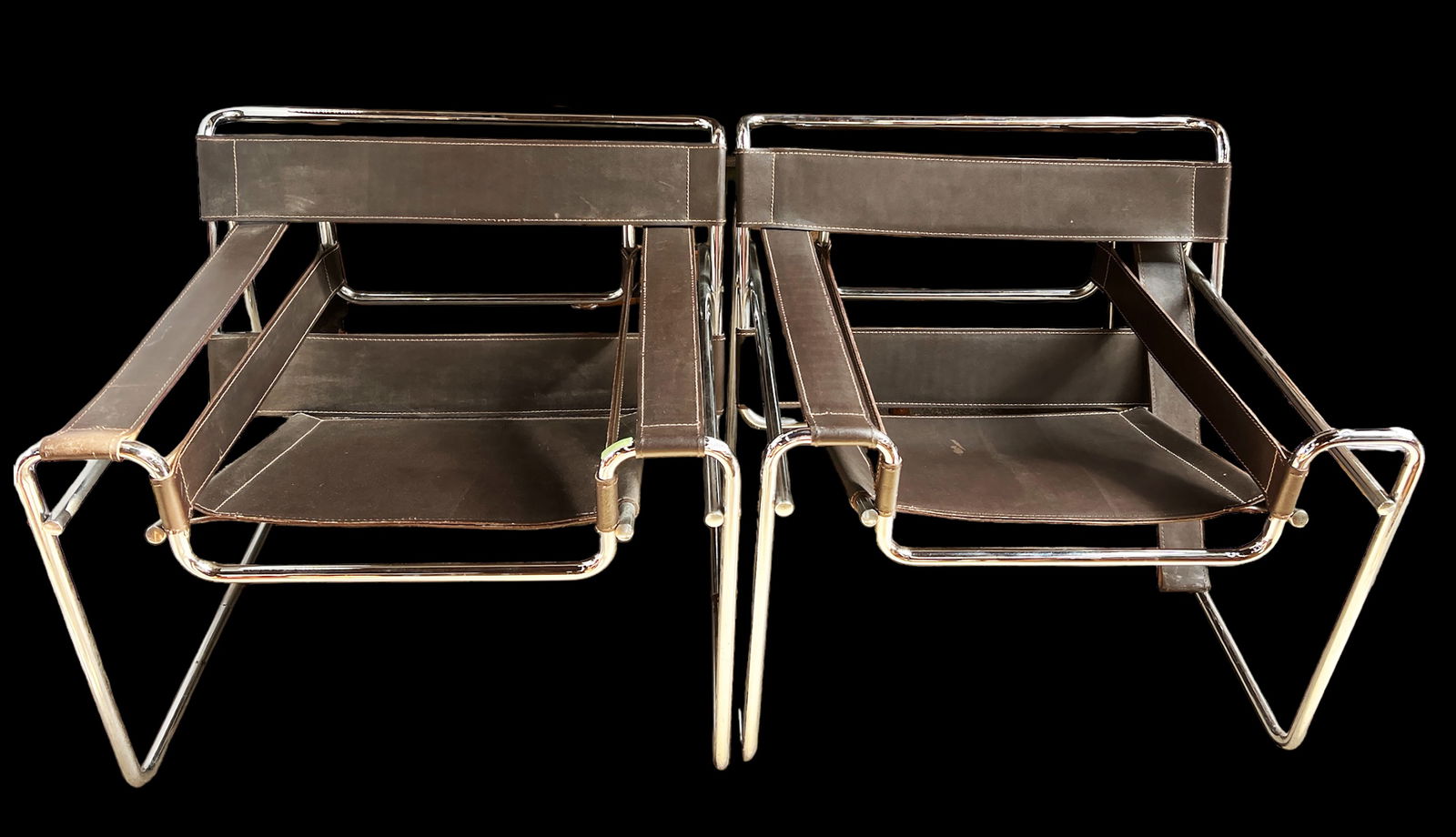 Pair of Italian Wassily Leather & Chrome Armchairs: One of the chairs is marked "Made in Italy." The chairs have dark brown leather backs, seats, and armrests. The frames are chrome. One of the chairs has a leather armrest that needs to be reattached.