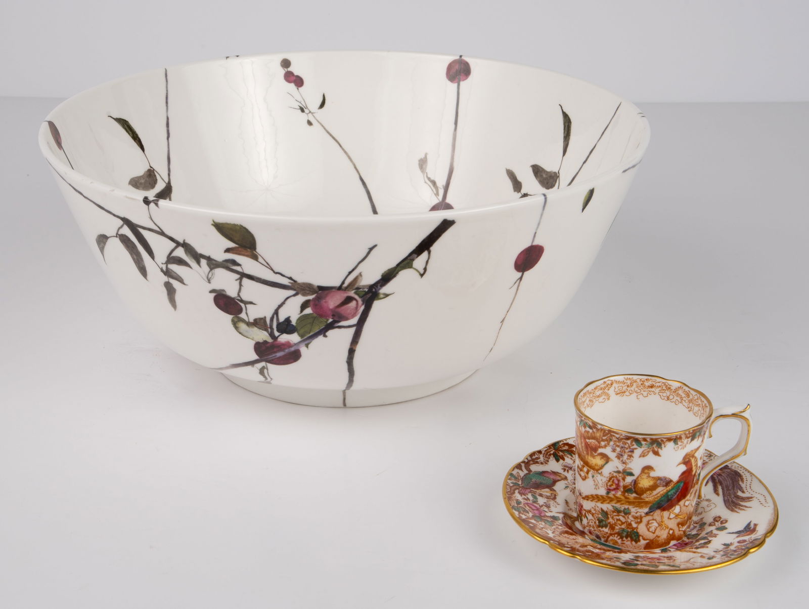 Lot: Royal Crown Derby, Andrew Wyeth Royal Doulton: The lot includes a Royal Crown Derby "Olde Avesbury" chocolate cup and saucer, and an Andrew Wyeth for Royal Doulton fruit bowl with apple tree design. The lot looks to be in good cosmetic condition.