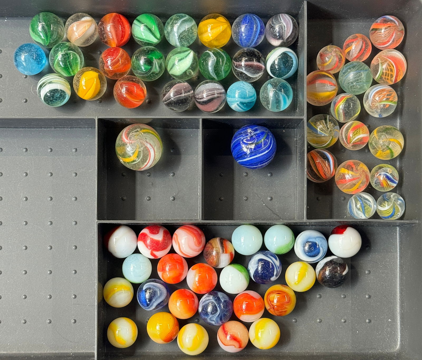 Marbles: 3 Swirl, 15 Latticino, 23 Cats Eye, Etc.: The lot consists of a total of 67 vintage glass marbles. First, there are 18 swirl marbles, 15 of them with latticino core. Out of the latticino core pieces, there is a shooter with a diameter of 15/1