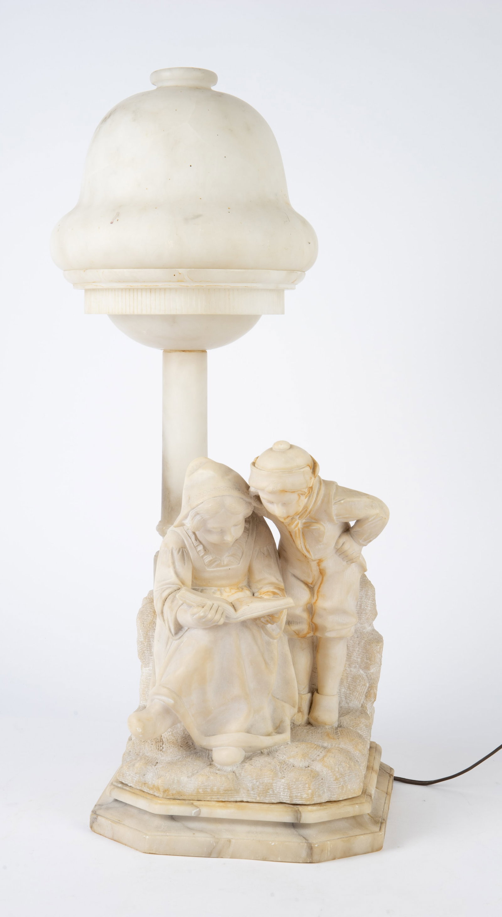 Carved Antique Alabaster Lamp of Children Reading.: It is signed on the back, though the signature is a little difficult to make out. There are some stains, scratches, and nicks present, and part of the base has been repaired. The lamp measures 24 1/2"