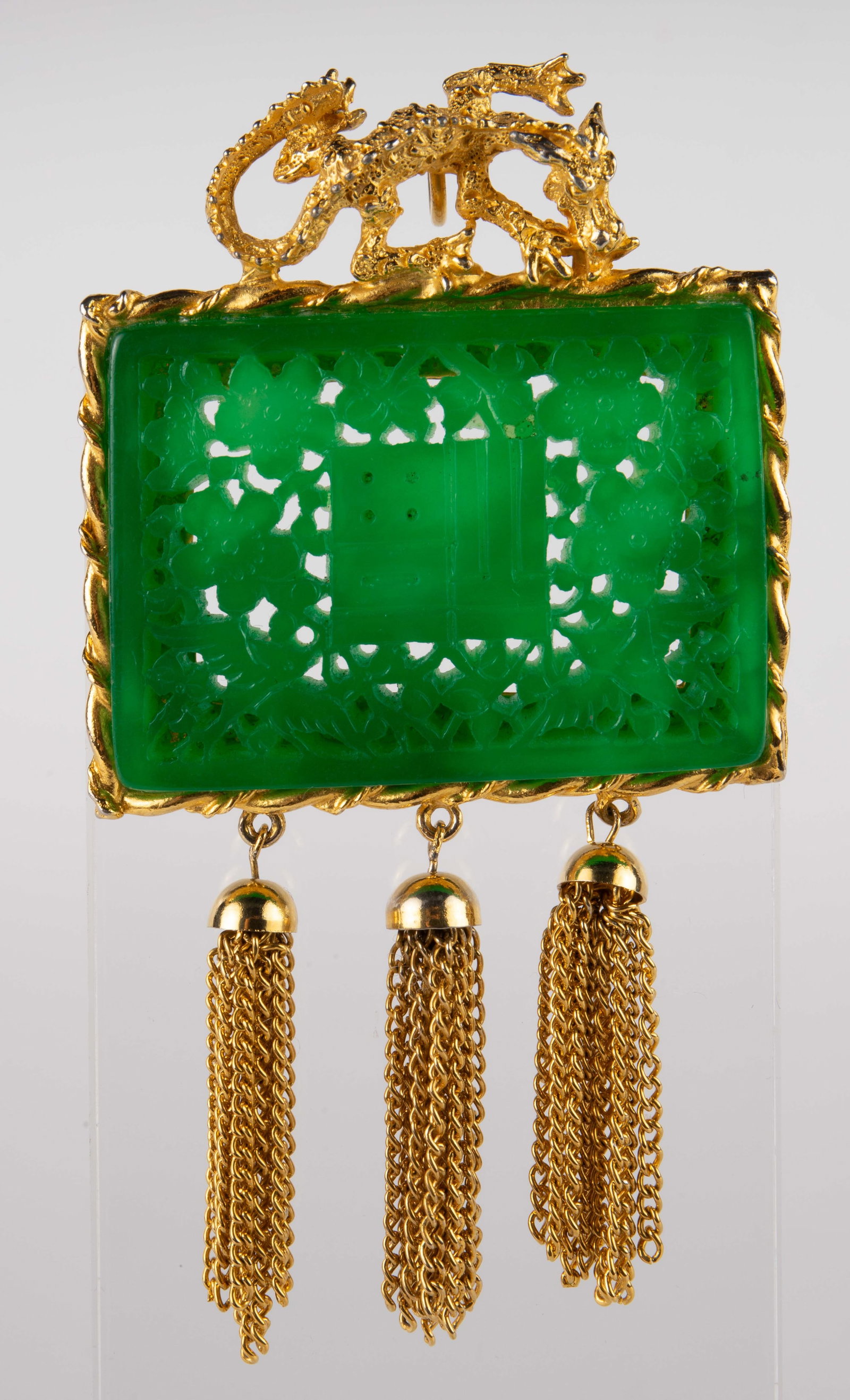 Gilt Hattie Carnegie Green Stone Brooch / Pendant.: The oriental style piece is signed Hattie Carnegie on the back. It features a large carved green stone. It measures 4 1/2" x 2 1/2". There is some discoloration on the dragon and frame. Otherwise, the