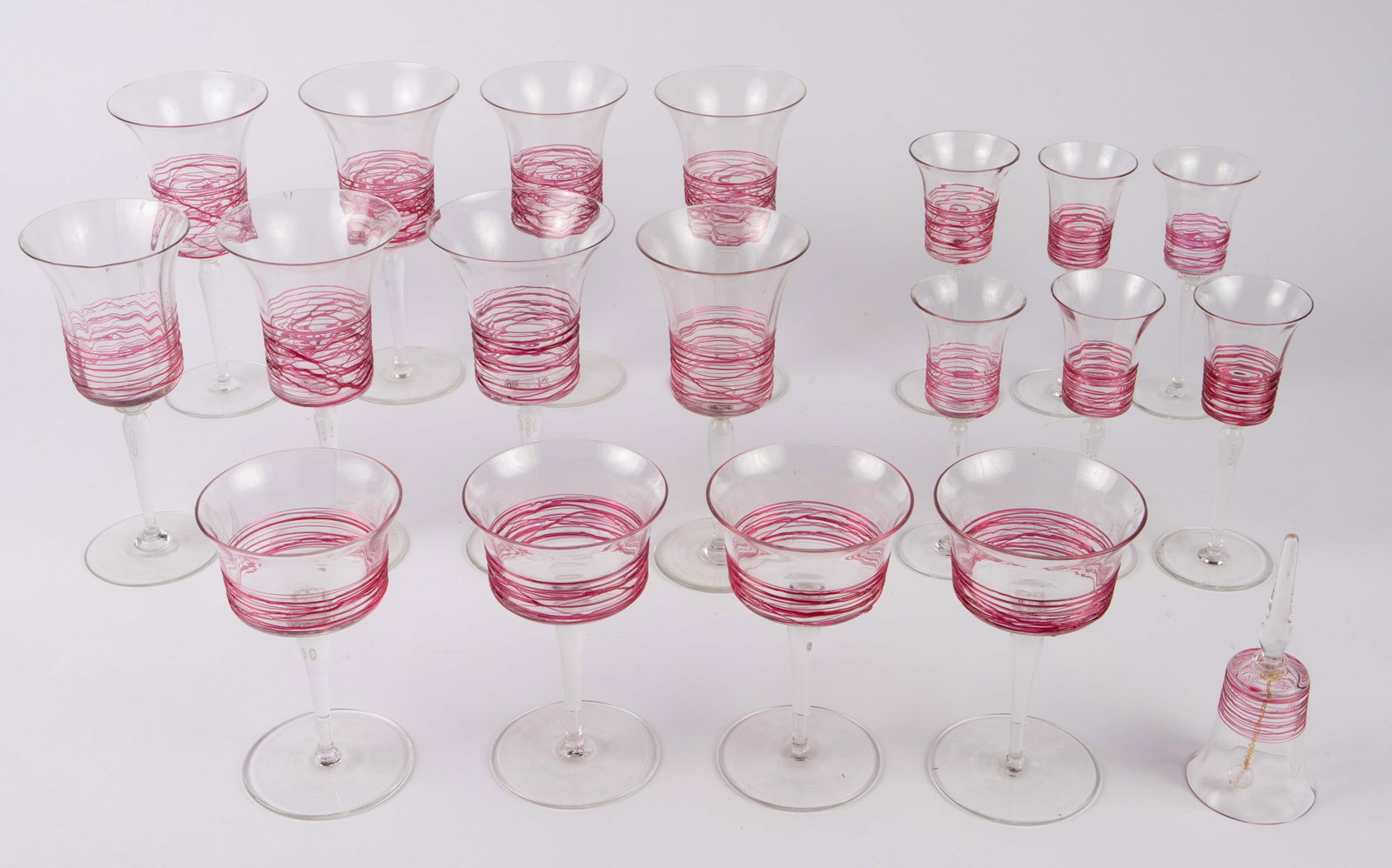 Steuben Carder Pink Threaded Stemware & Bell.: This lot consists of 18 pieces of glass stemware and one bell designed by Frederick Carder for Steuben. There are 8 fluted wine glasses, 6 fluted cordial glasses, and 3 sherbets. The smallest piece in