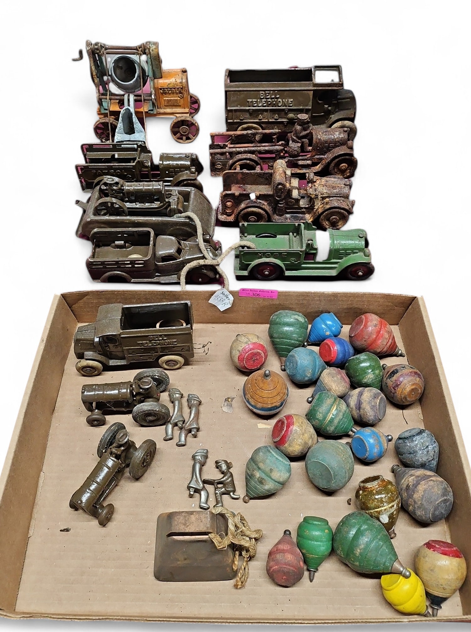 Lot of Vintage Toys- Cast Iron Cars, Spinning Tops: This lot includes painted wood tops, a cowbell, firefighter metal figures, and several cast iron cars. There are fire trucks, patrol cars, and telephone trucks. The condition varies- some items are in