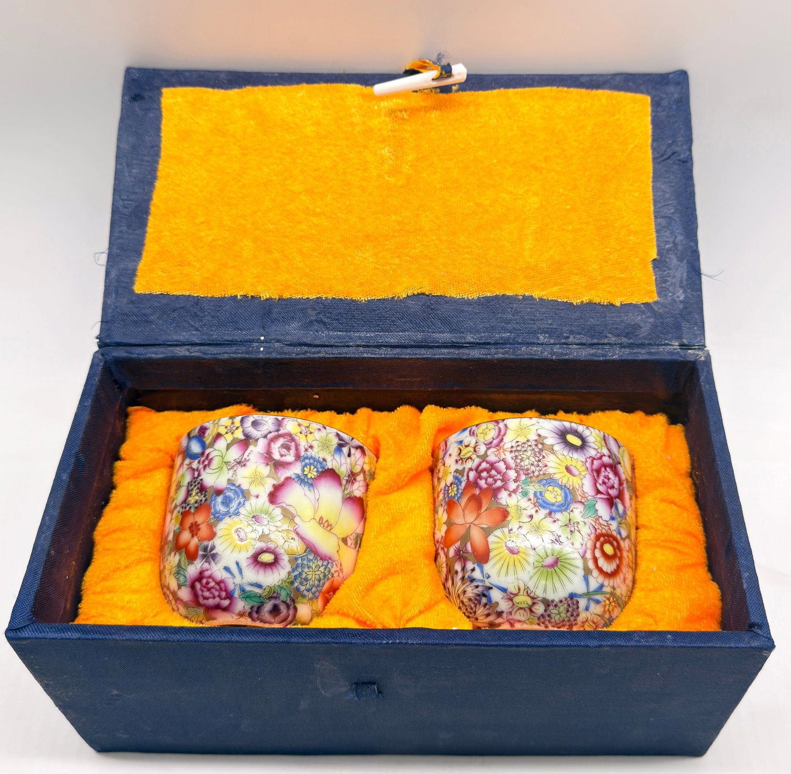 Pair of Hundred Flower Chinese Porcelain Cups.: Each of the cups has a mark on its underside. They come in a blue box or holder. The cups are in good condition. Each cup measures 2 3/4" tall and 3 1/8" in diameter. In-house shipping is available. P