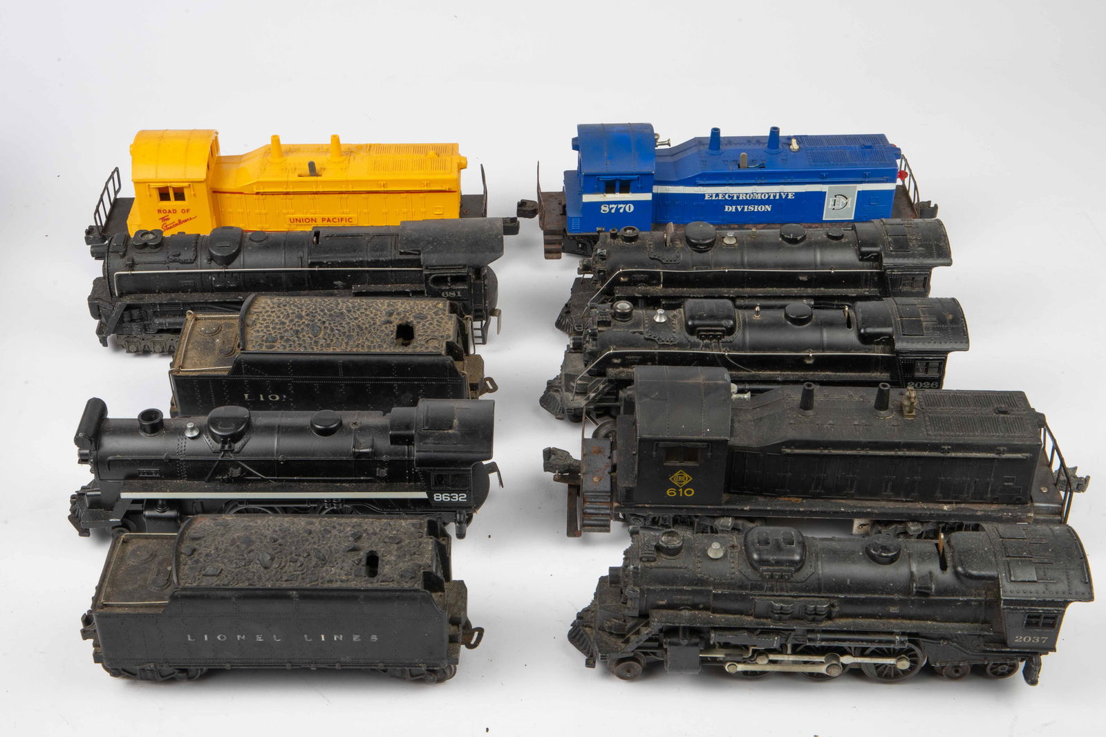 Lot of Lionel O Gauge Locomotives & More.: The lot includes 10 items in total. Some are plastic and some are cast metal. The engines included are 2026, 2037, 8632, 681, and 1666. There are also 2 Lionel Lines coal tenders, and three diesel swi