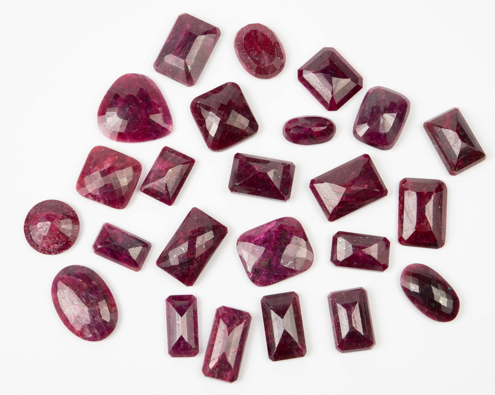 Lot of Large Cut Rubies - 1500 Carats Total.: The lot contains 24 ruby stones cut in different shapes. The smallest piece, which measures 24mm x 14mm x 9mm, weighs 29.84 Carats. The largest piece measures 29mm x 25mm x 12mm, and weighs 99.56 Cara