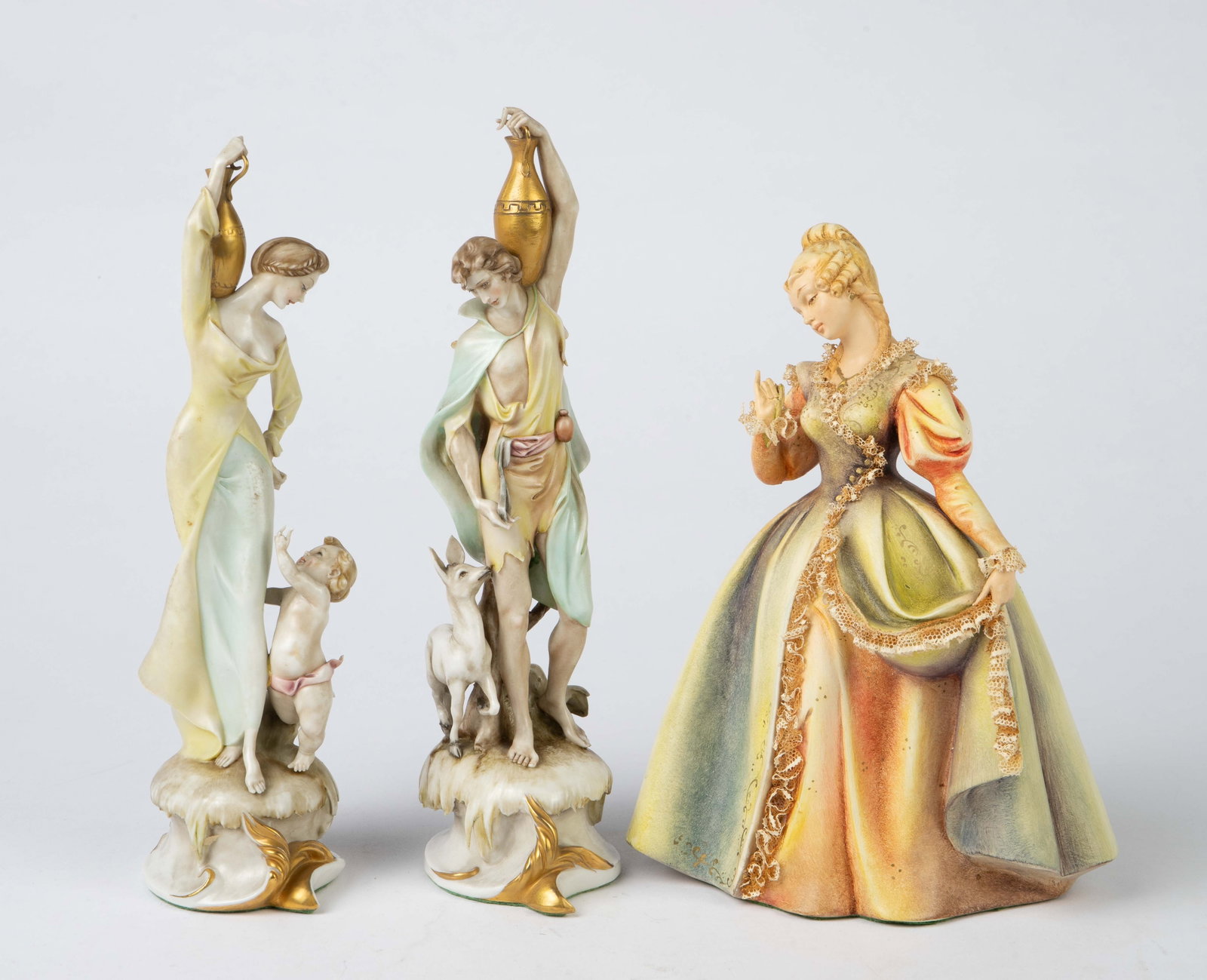 Lot of 3 Borsato Figurines- Two Are a Pair.: The pair of figurines are a man and woman with golden urns. She has a child or Putti at her feet, and he has a baby donkey at his side. His left leg has been repaired. There is also a third Borsato fi